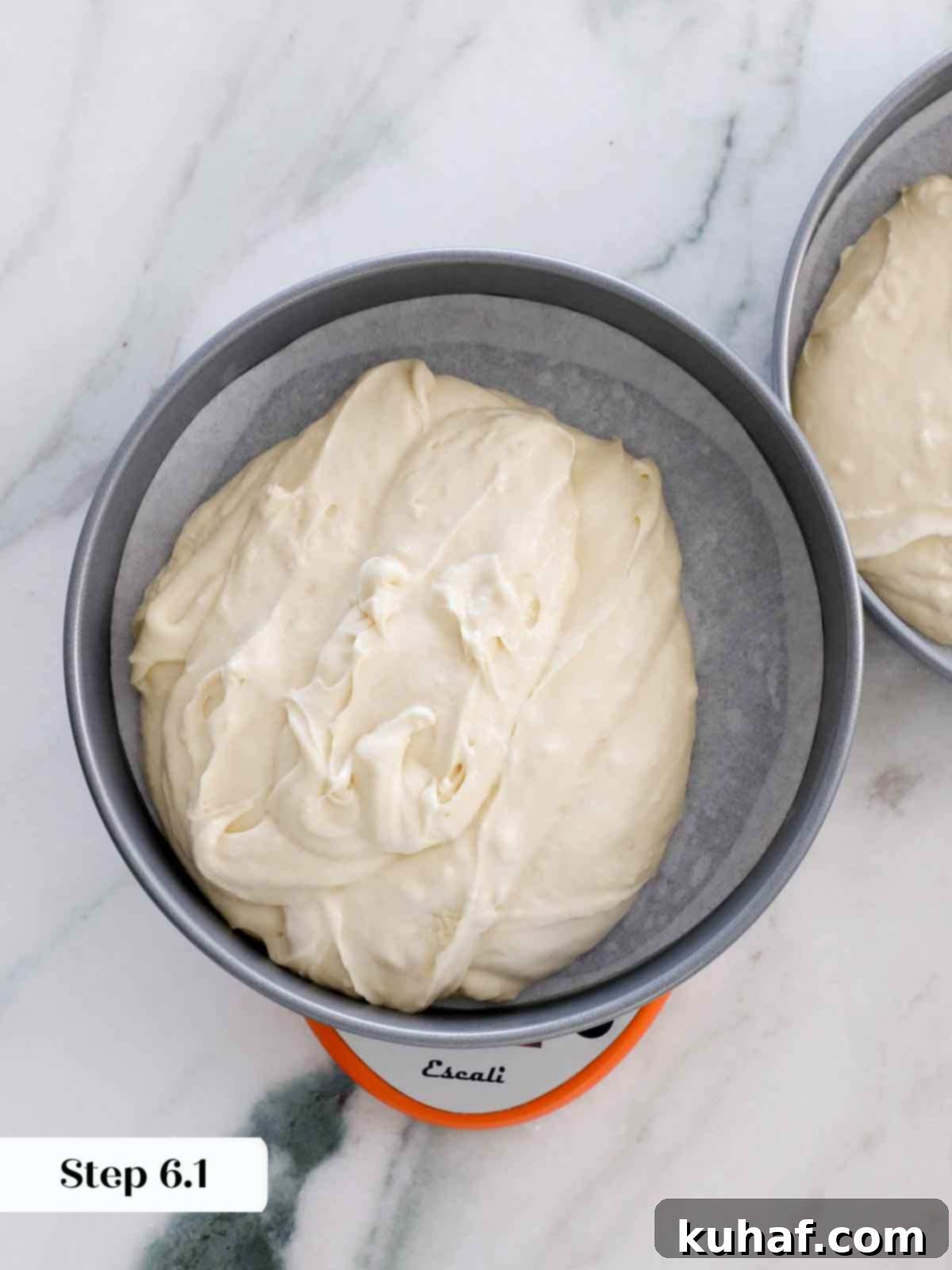 Dividing vanilla cake batter evenly between two cake pans.