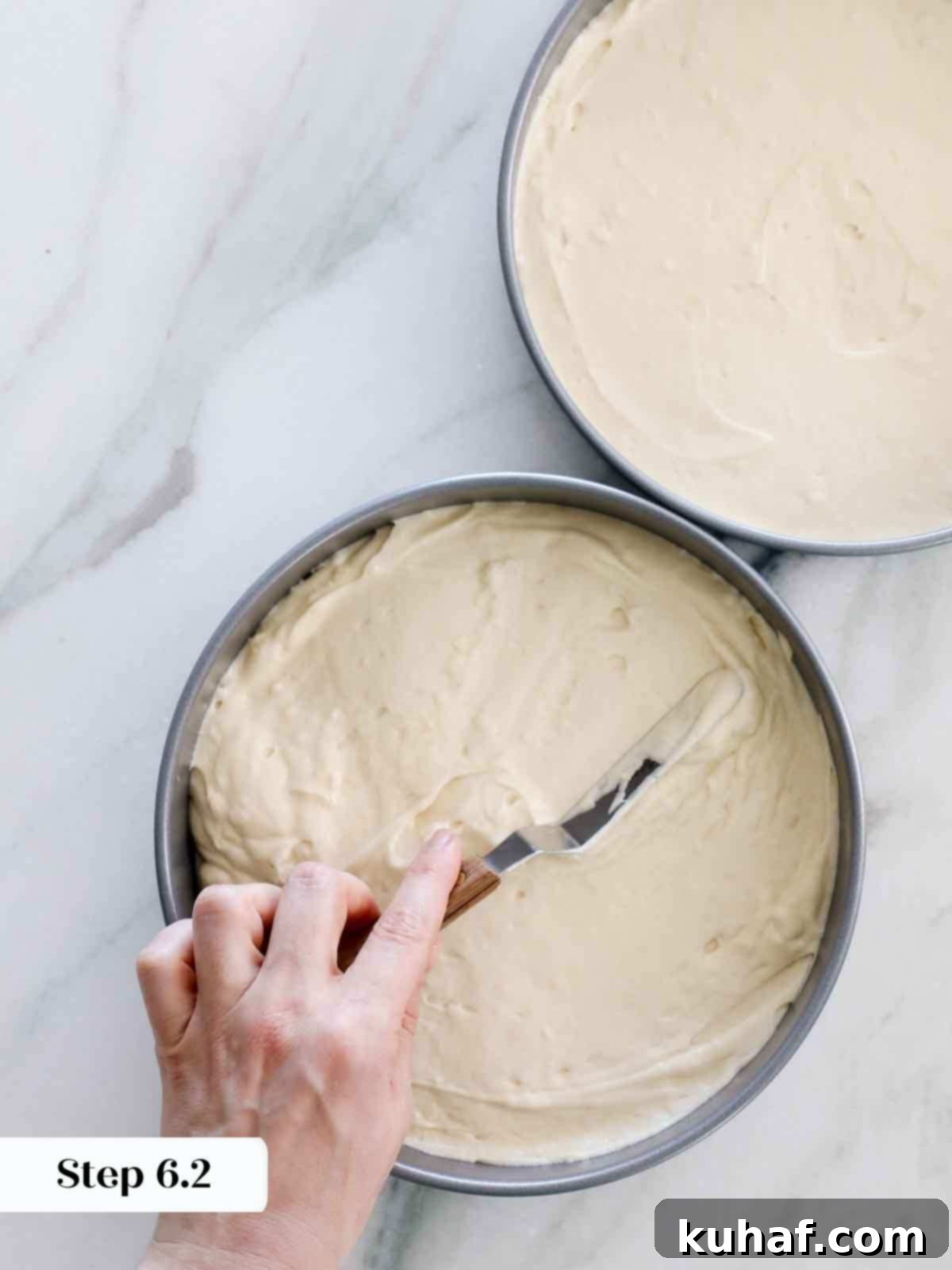 Smoothing out vanilla cake batter in pans with an offset spatula.
