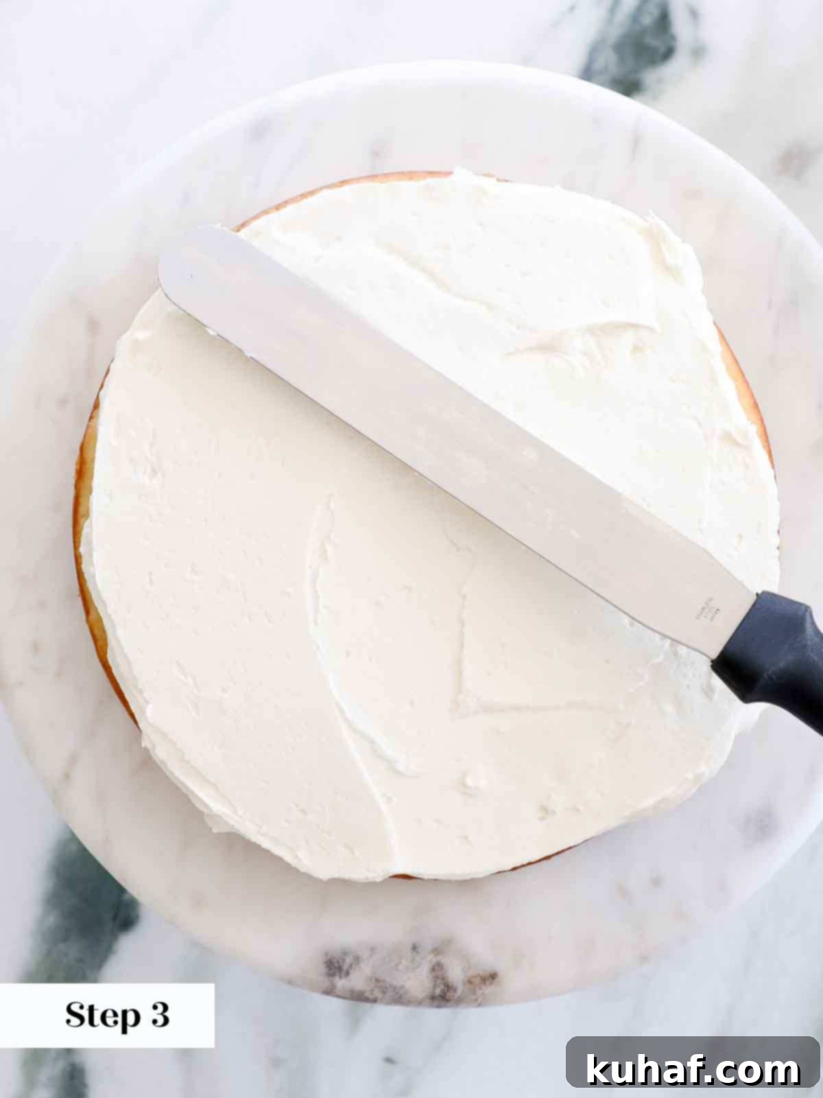 Smoothing out buttercream between cake layers with an offset spatula.