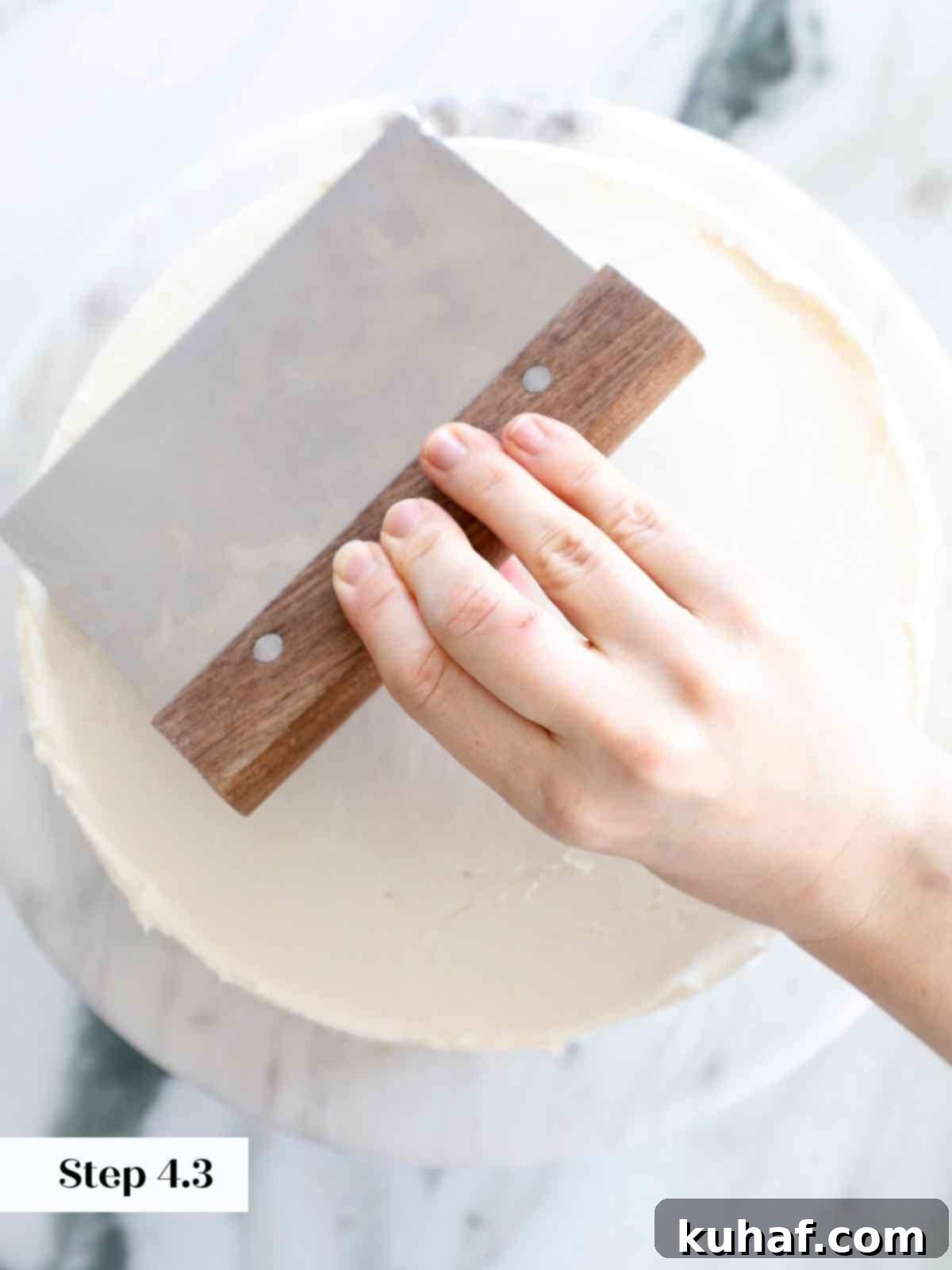 Smoothing the top of a vanilla cake with an offset spatula for a pristine surface.