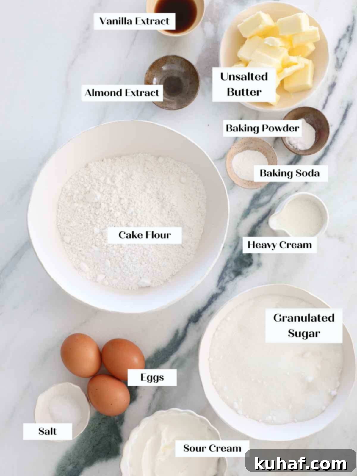 Essential ingredients for a moist vanilla cake arranged artfully on a marble surface.