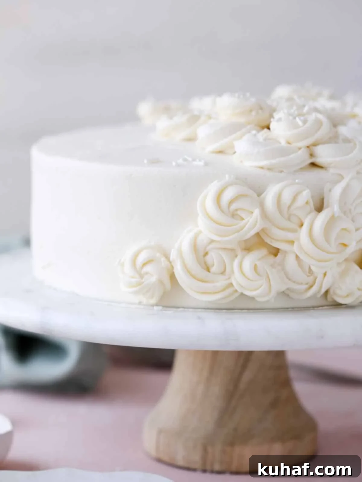 A stunning vanilla layer cake, beautifully frosted and presented on a elegant cake stand.
