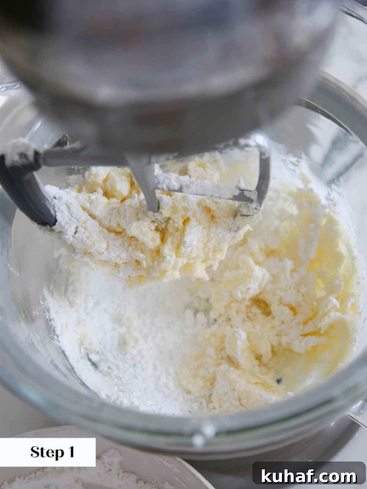adding sugar to butter in lemon buttercream frosting.