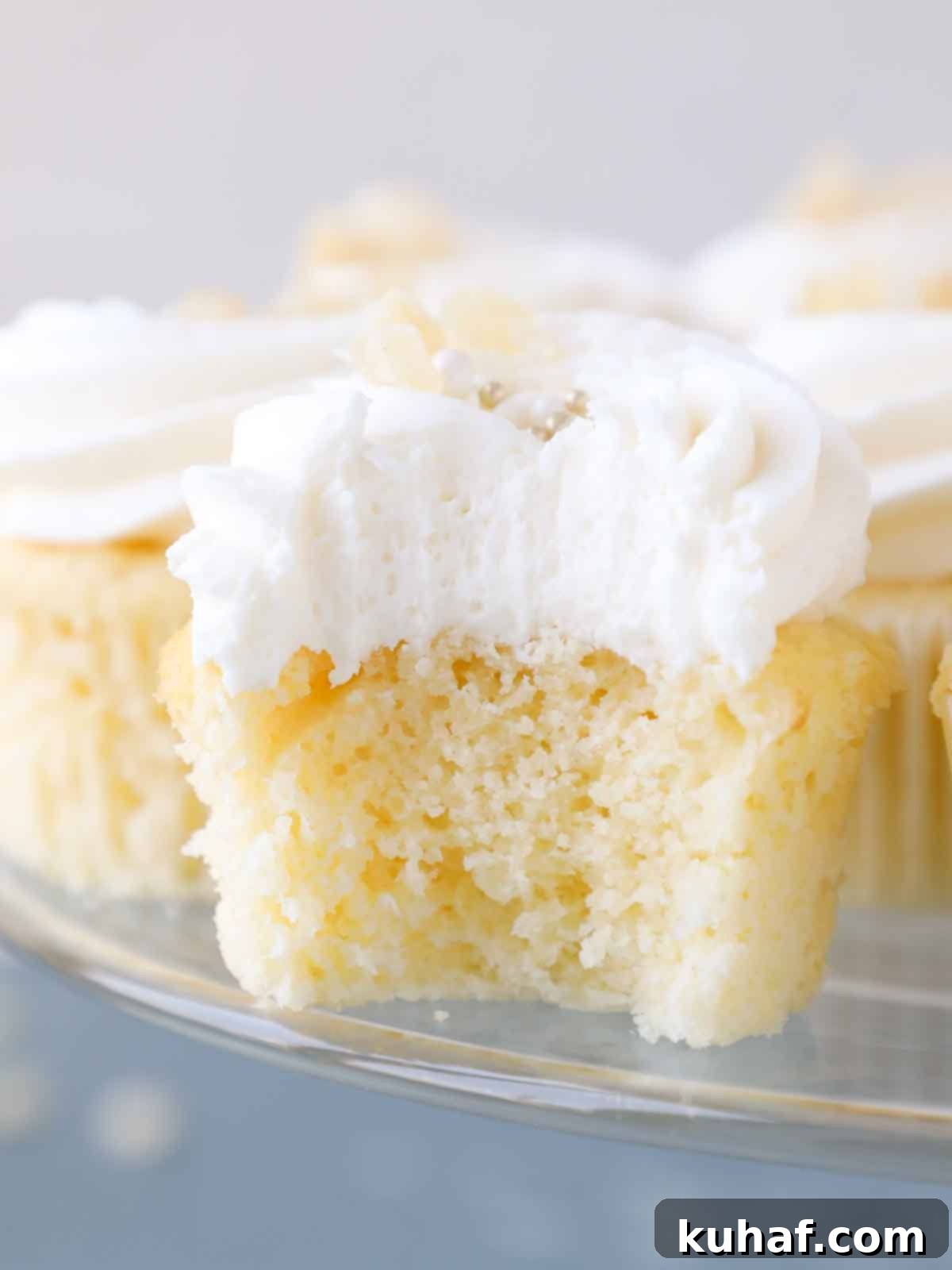 interior texture of lemon cupcake on clear cake stand and blue surface.