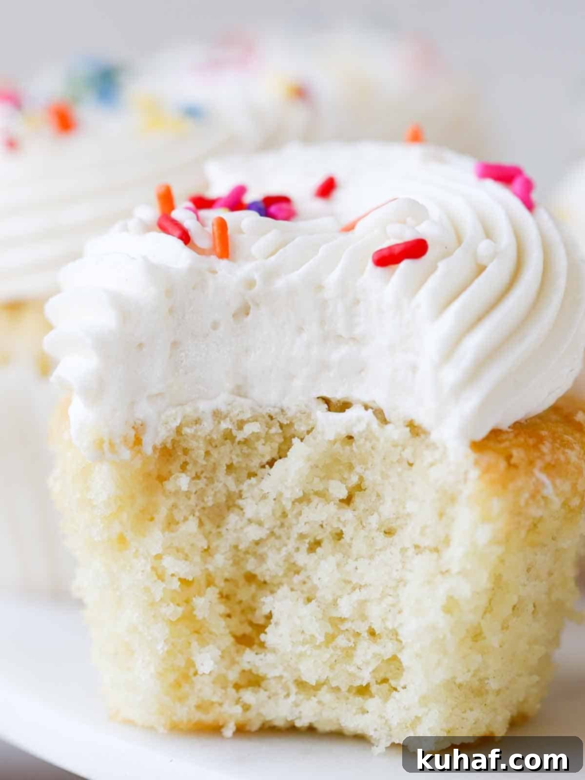 Soft, moist vanilla cupcakes with fluffy ermine frosting, showing the delicate interior texture.