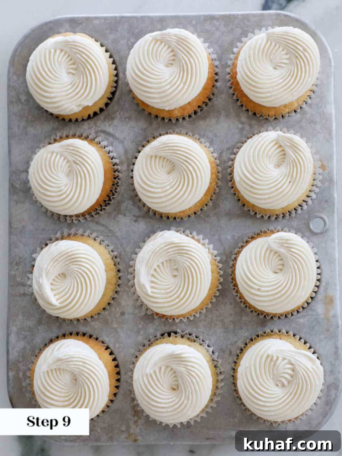 Frosted vanilla cupcakes with ermine frosting arranged in a vintage tin, ready to serve.