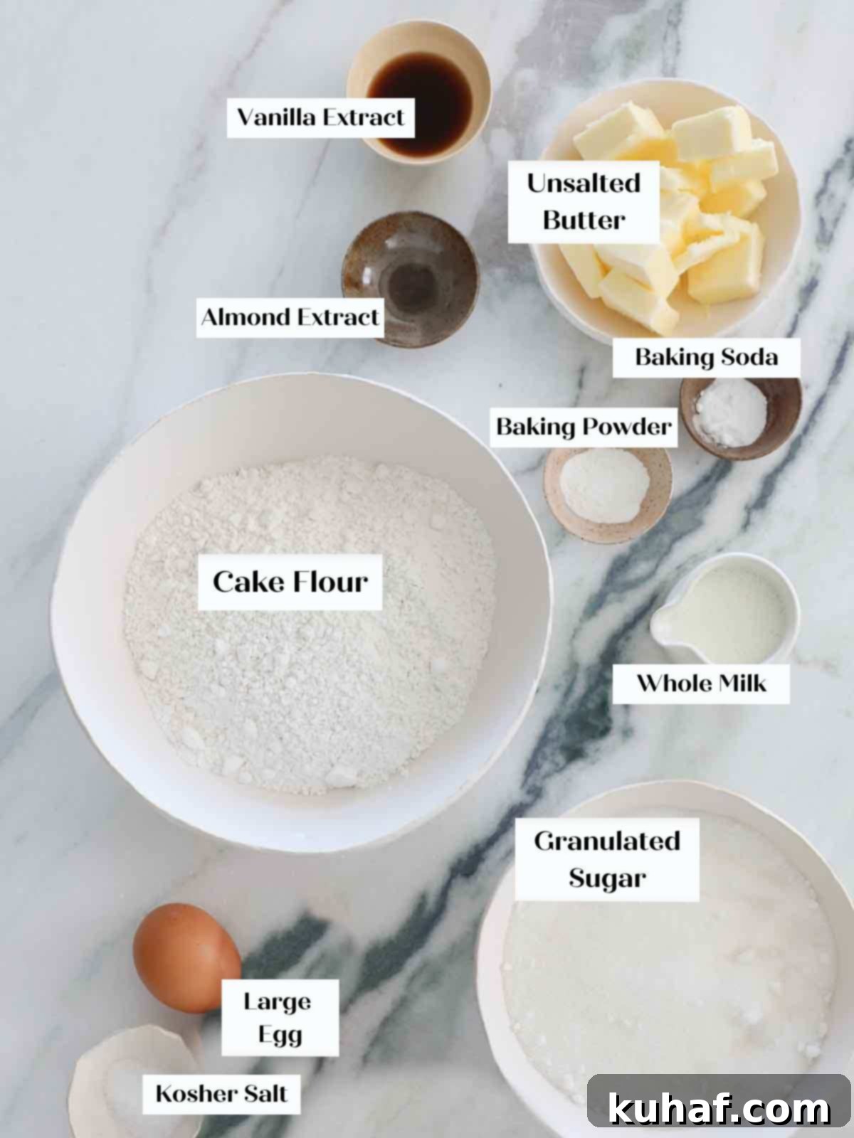 Carefully laid out ingredients for vanilla cupcakes on a clean marble surface.