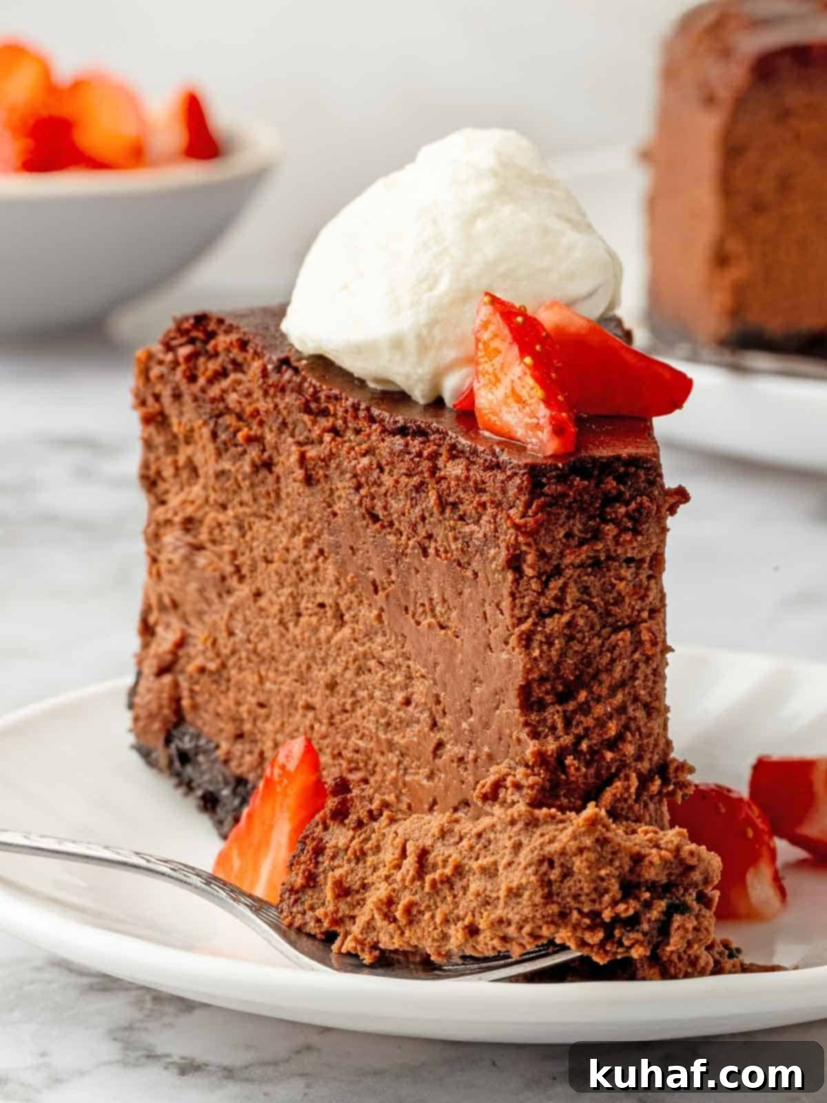slice of chocolate cheesecake with whipped cream and berries bite on fork.