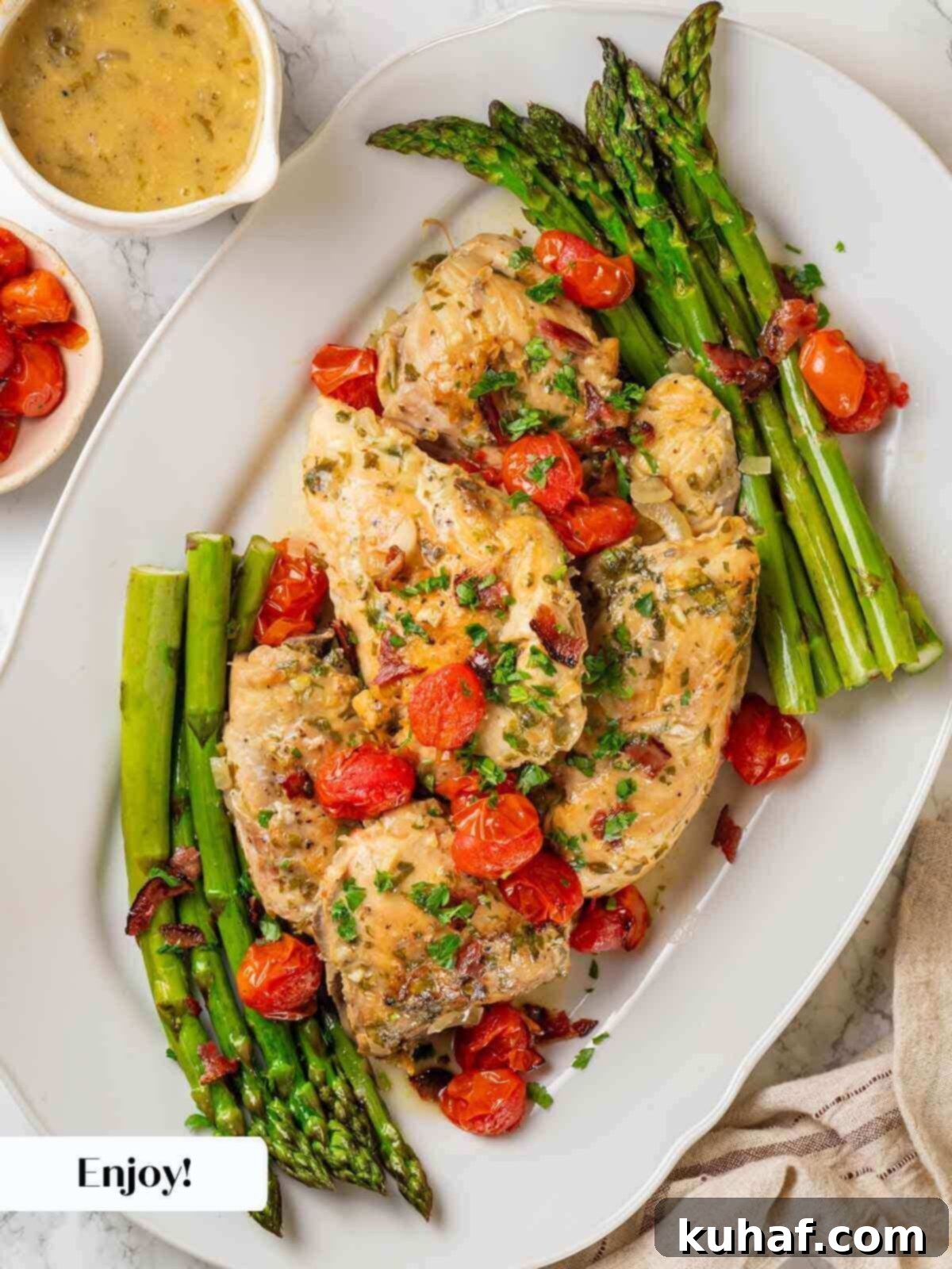Finished chicken in wine sauce served on a white platter, garnished with blistered tomatoes and fresh herbs.