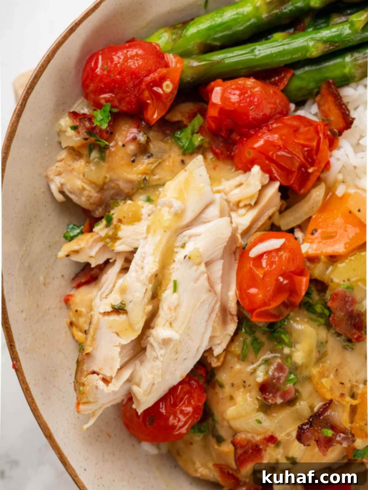 Chicken in wine sauce served on a plate with asparagus spears on the side.