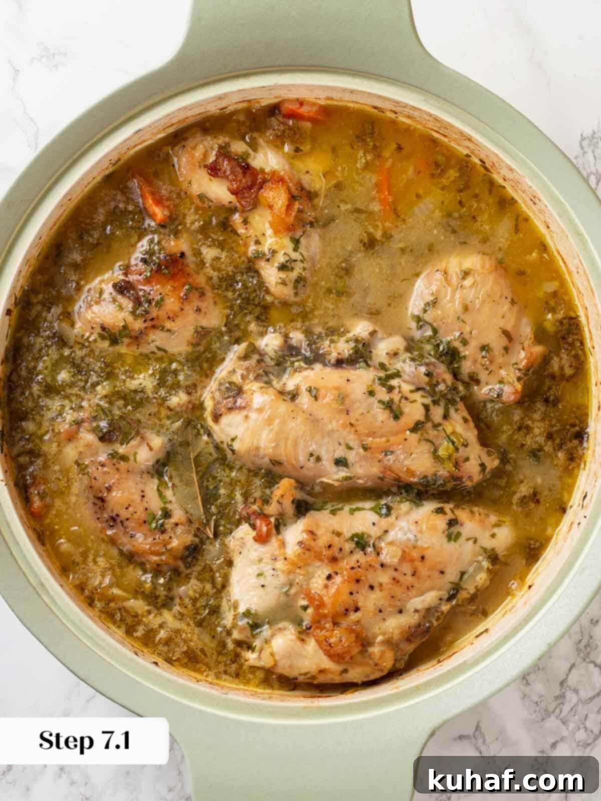 Chicken in wine sauce baked in a skillet, ready to be removed from the oven.