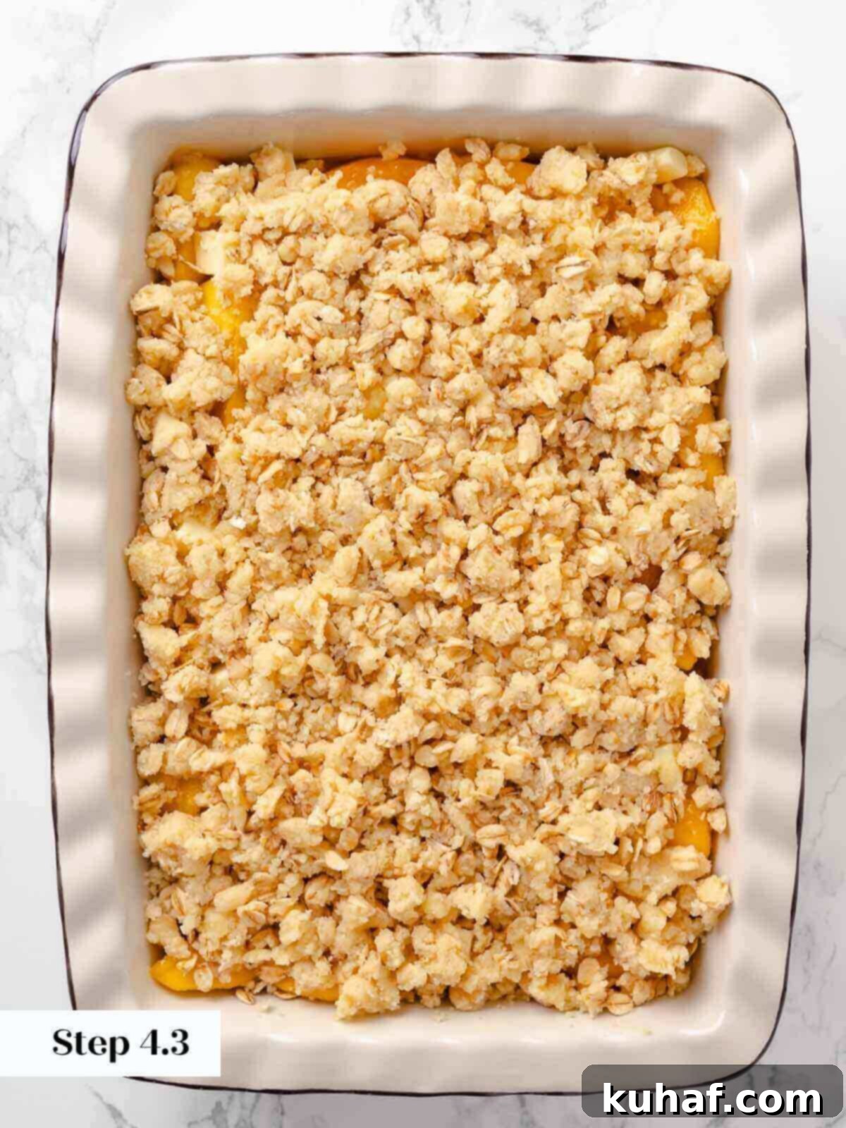 Peach crisp ready to bake, with a crumbly topping covering the peach mixture.