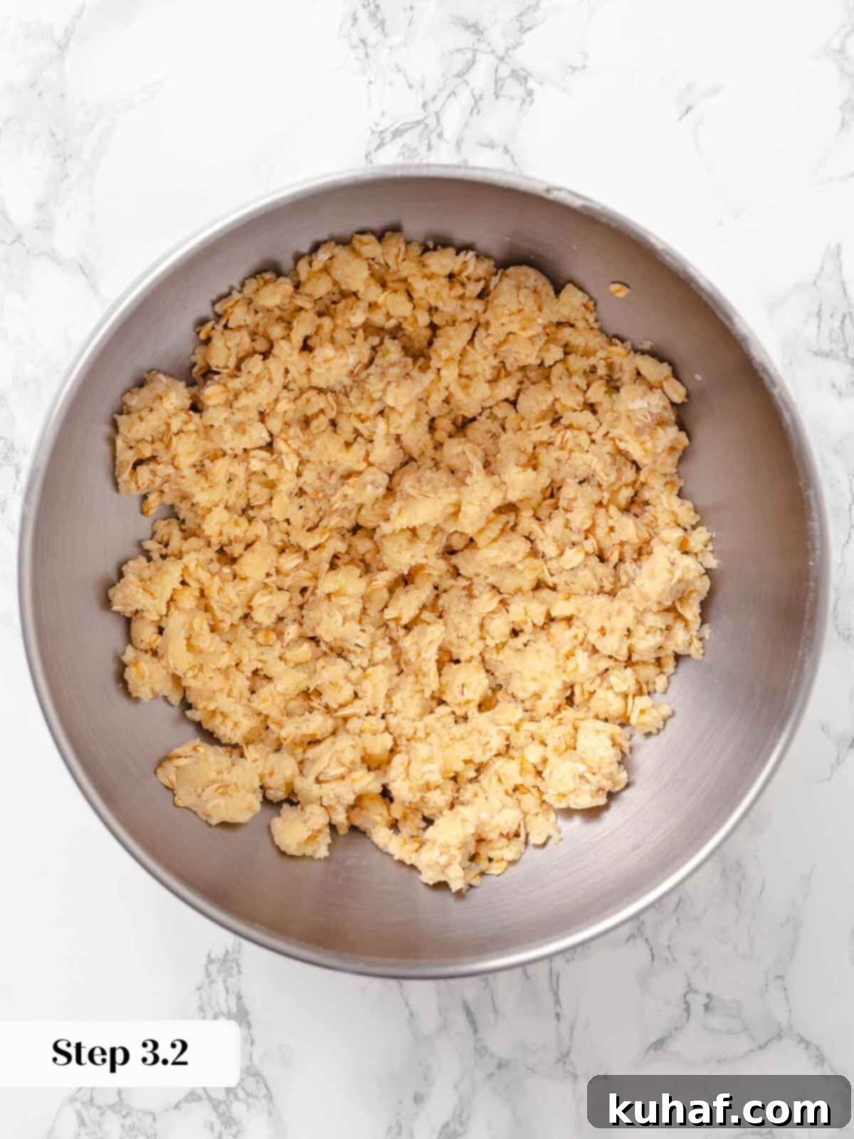 Streusel topping for peach crisp in a silver bowl, showing the crumbly mixture.