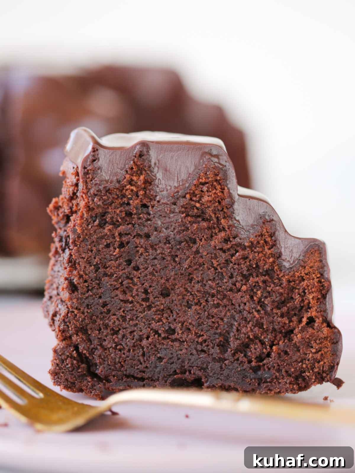 slice of chocolate bundt cake with ganache on gold cake server. 