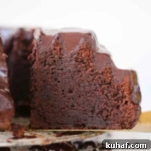 slice of chocolate bundt cake with ganache on gold cake server.