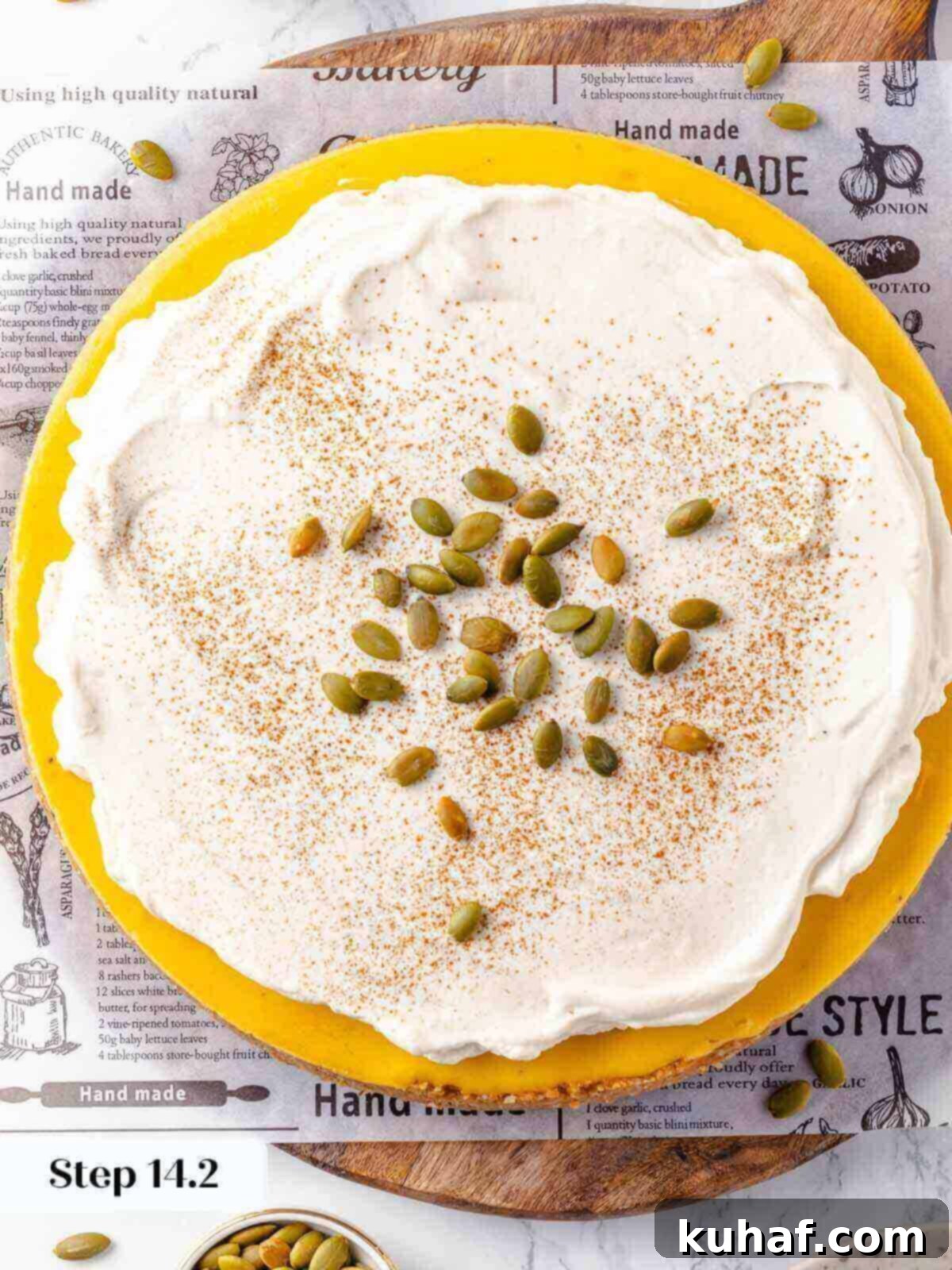 Decadent Pumpkin Cheesecake 21 A slice of pumpkin cheesecake topped with a swirl of spiced whipped cream and a dusting of cinnamon.