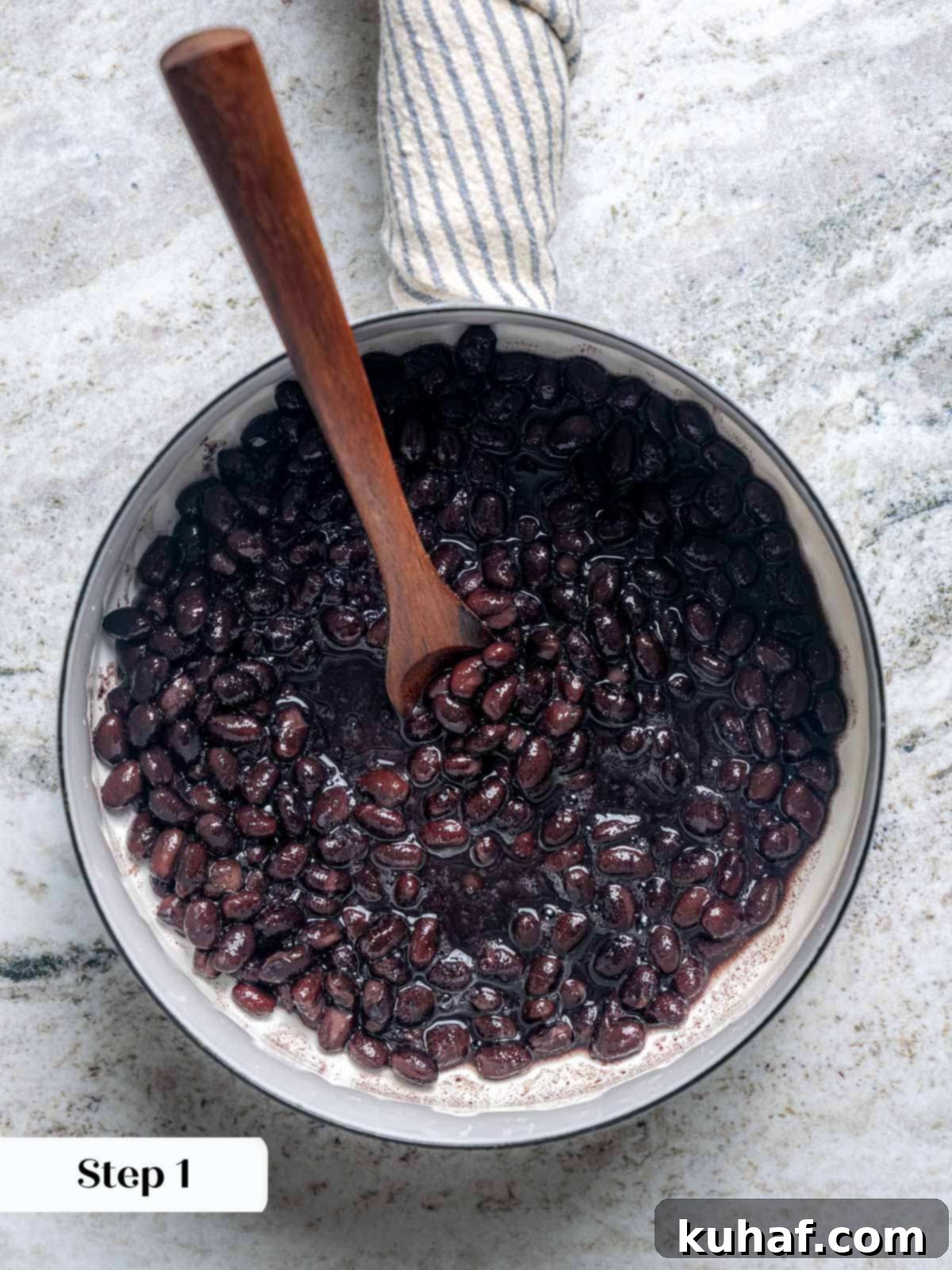 Black beans simmering in a white bowl, ready to be served with the tacos.