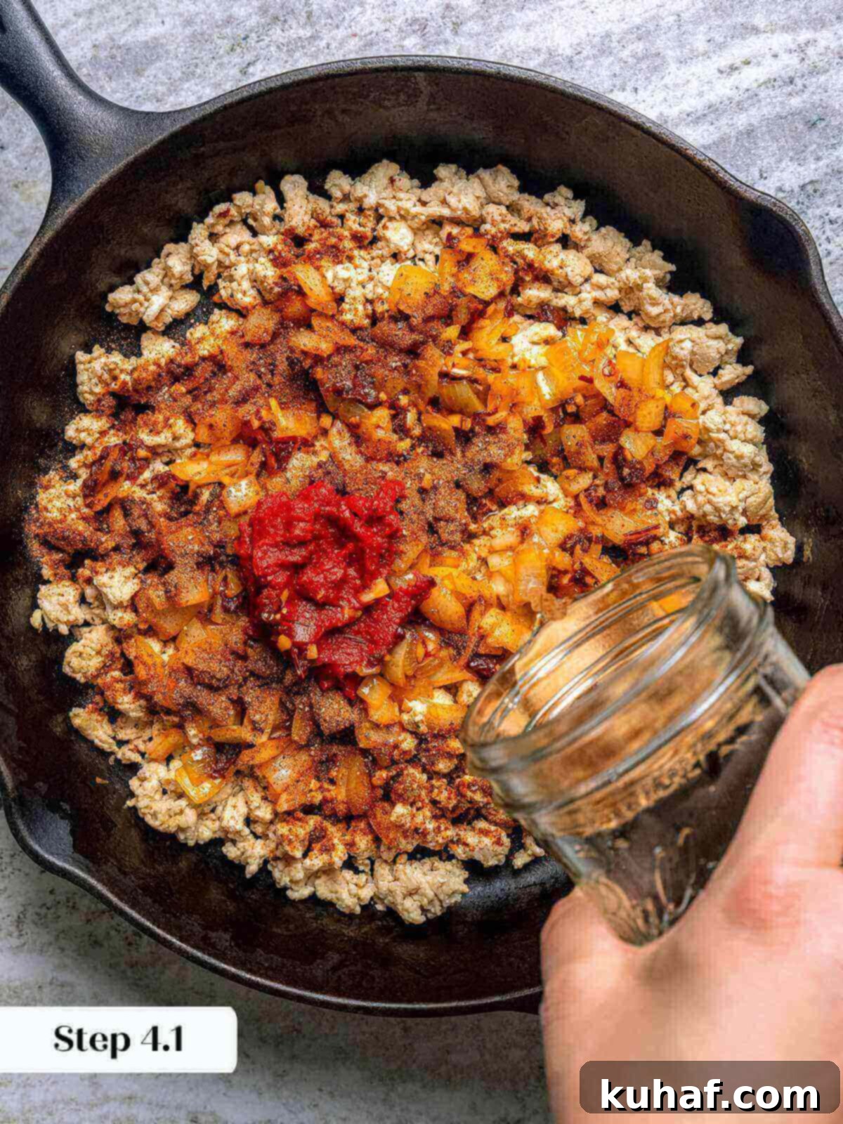 All the cooked ingredients, including browned ground chicken, onions, and spices, mixed together in a large skillet.