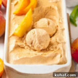 scoops of fresh peach ice cream in white loaf pan with slices of peaches.