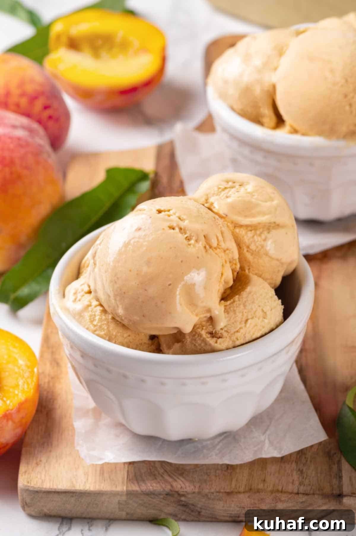 Delicious scoops of fresh peach ice cream in a pristine white bowl, ready to be enjoyed.