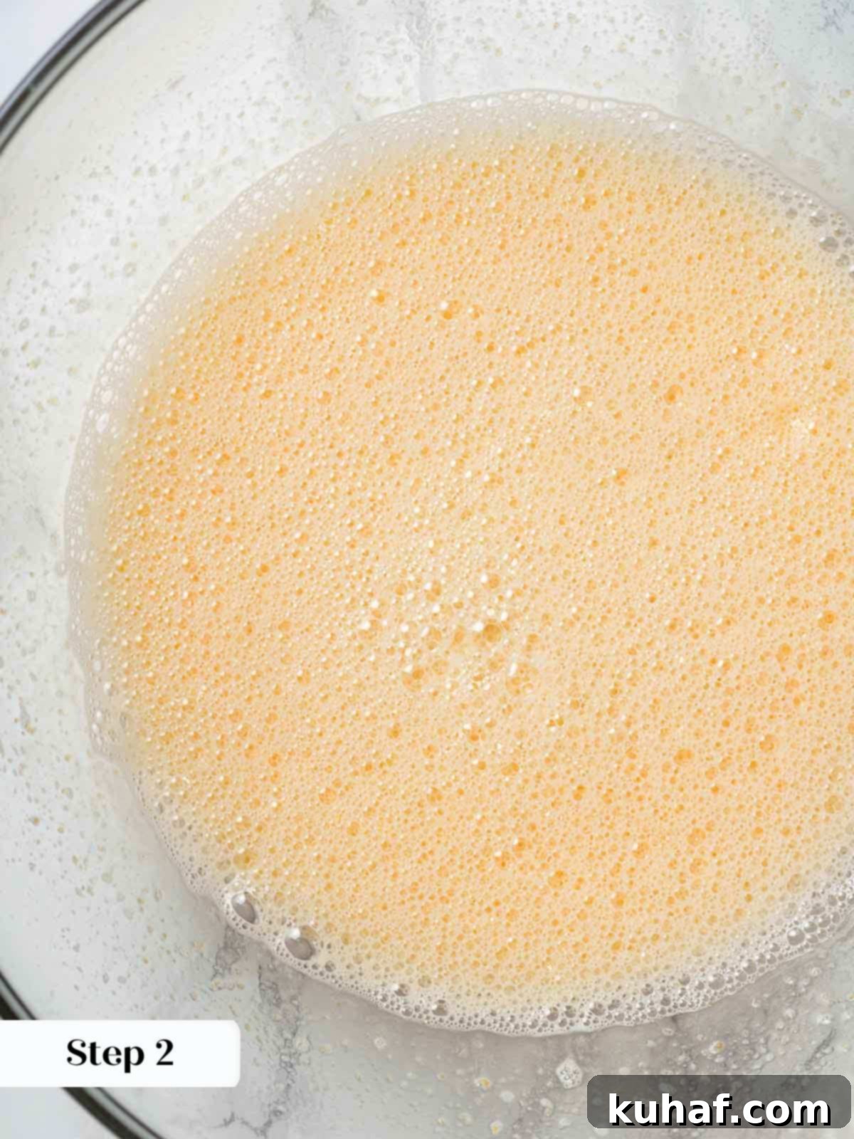 Close-up of whisked eggs and sugar, forming a smooth base for the ice cream.