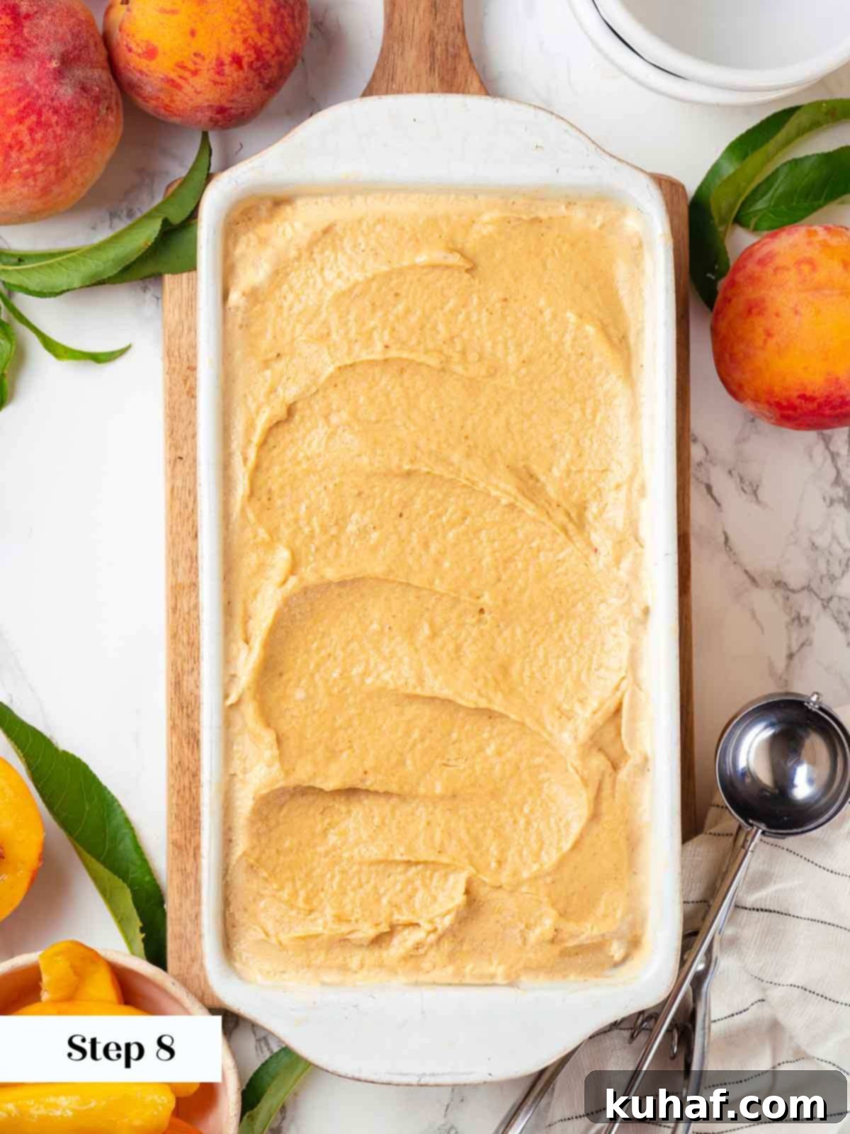 Smooth fresh peach ice cream spread evenly into a container, ready for the freezer.