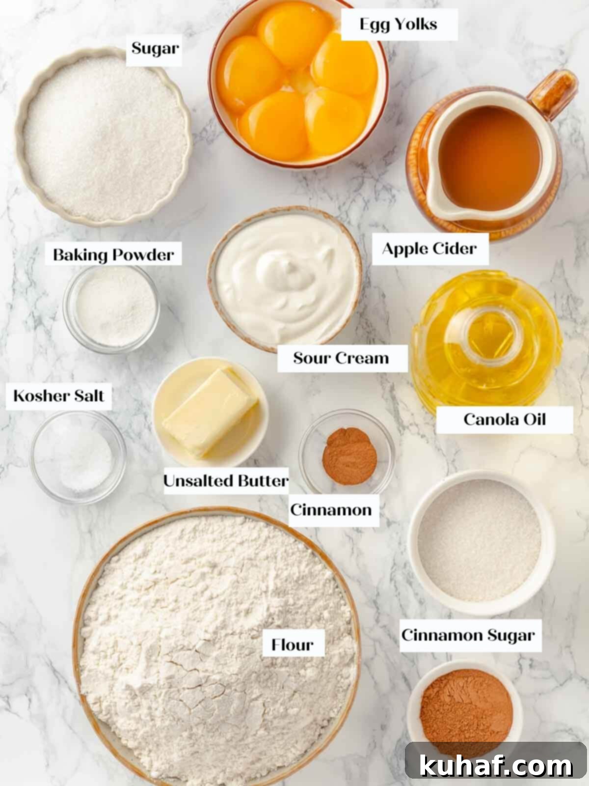 Ingredients for apple cider donuts laid out on a white marble countertop.