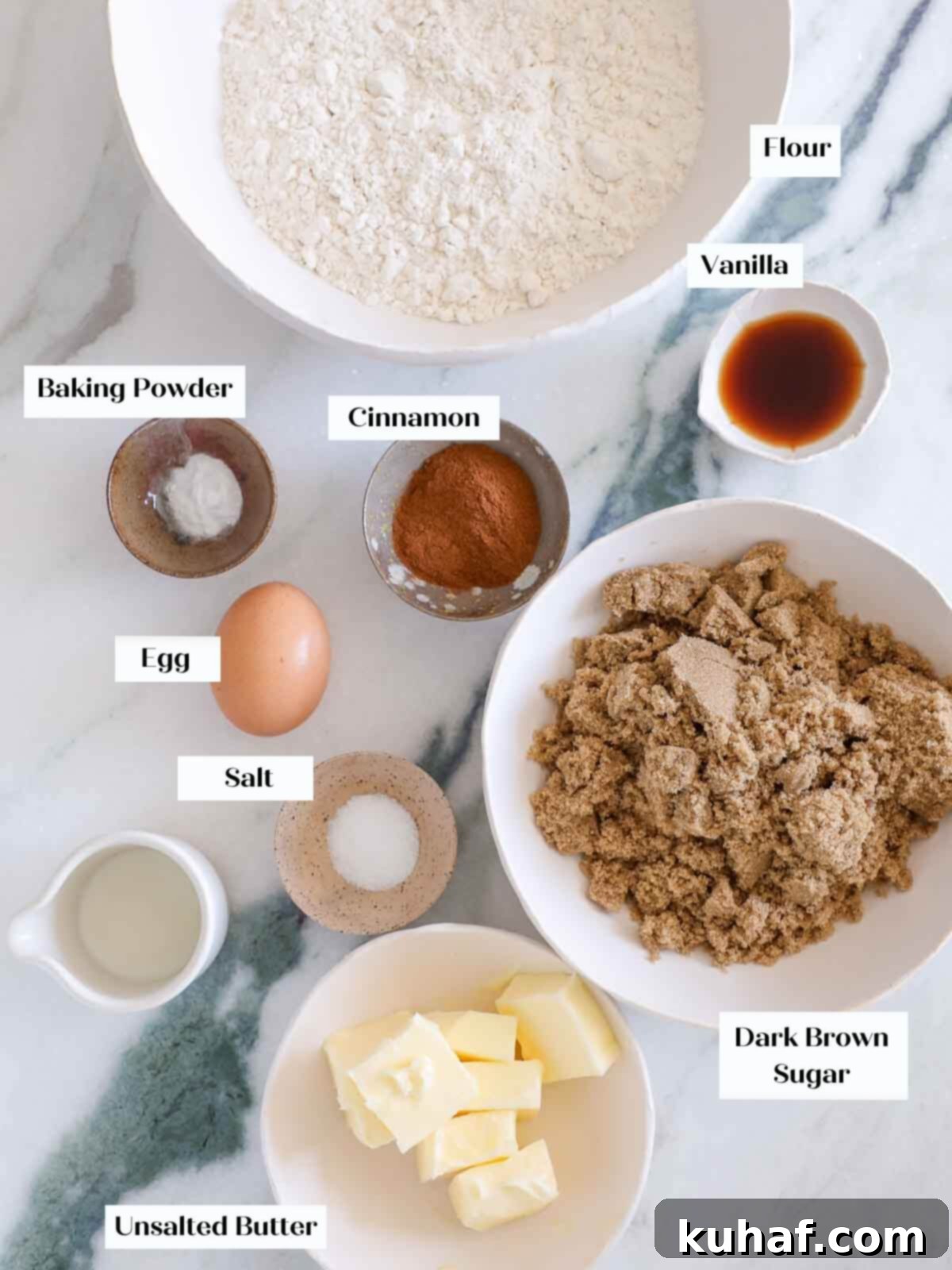 Warm Spiced Sugar Delights 4 Ingredients for cinnamon sugar cookies laid out on a white marble surface, including brown sugar, butter, eggs, flour, and spices