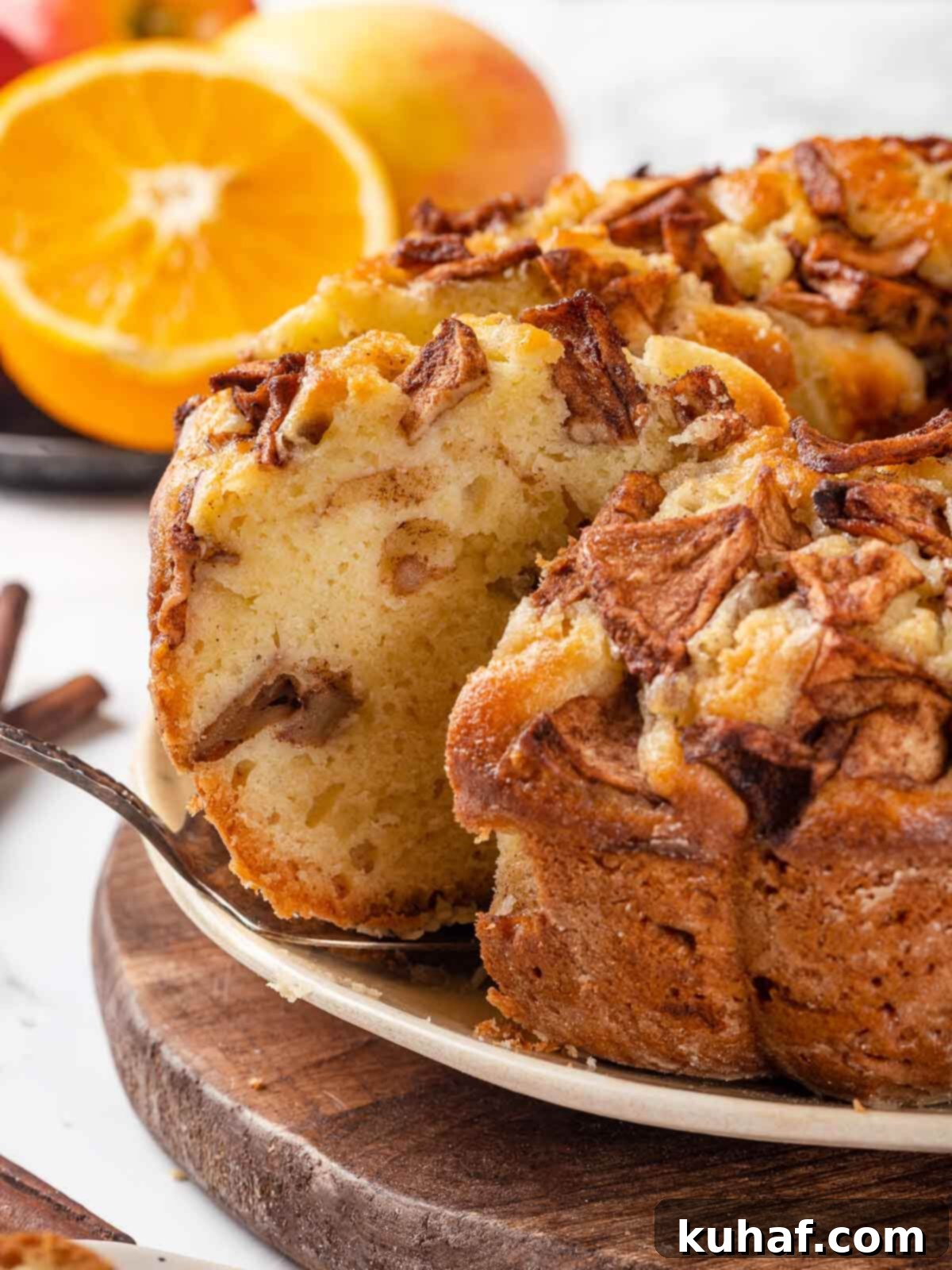 Jewish Apple Cake 2 A silver cake server next to a Jewish apple cake on a serving plate, highlighting its golden-brown crust and apple layers.