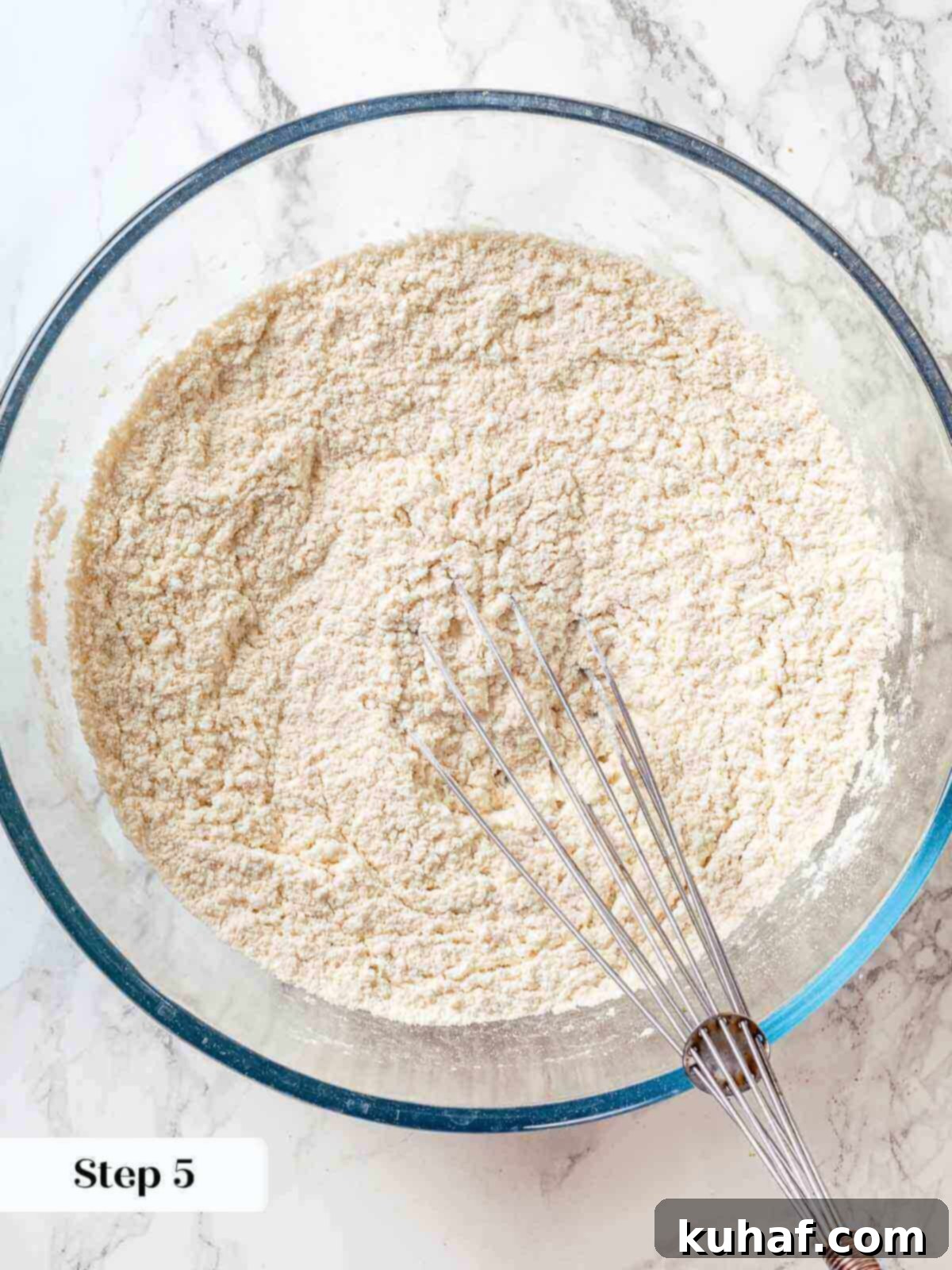 Jewish Apple Cake 6 A bowl of dry ingredients for Jewish apple cake, including flour, baking powder, and salt, being whisked together.