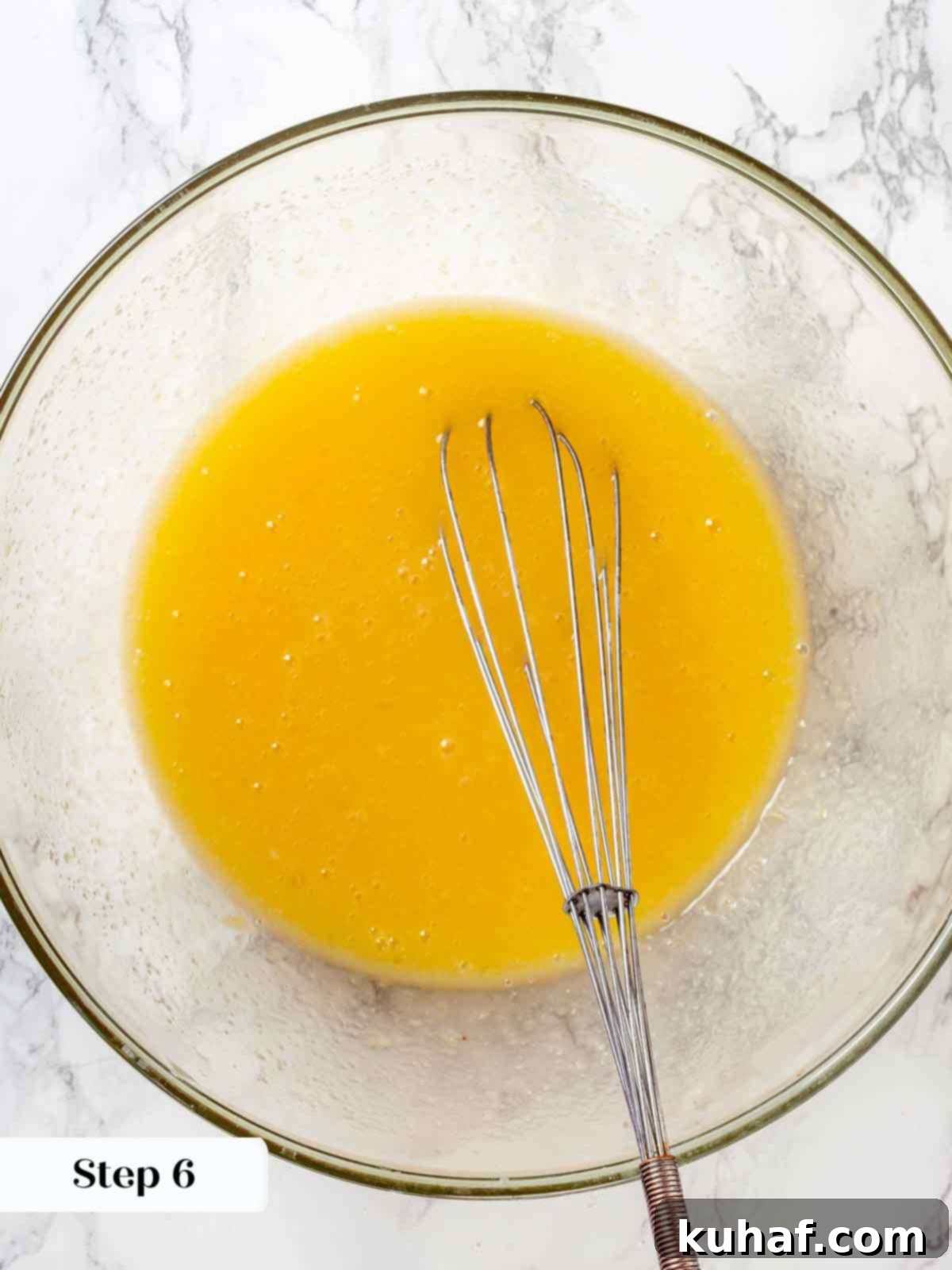 Jewish Apple Cake 7 A mixing bowl filled with a smooth, emulsified mixture of whisked eggs, oil, sugar, and orange juice.