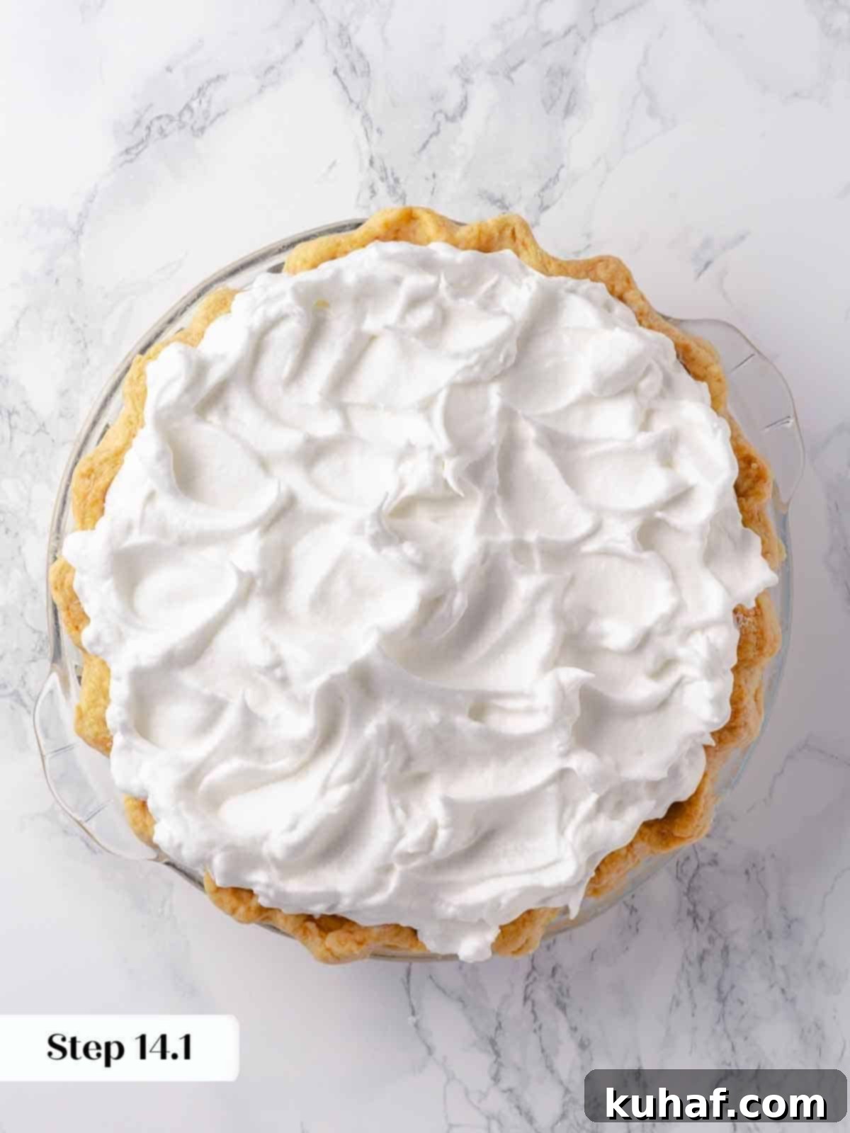 A pristine French-style meringue, artfully swirled into decorative peaks, covers the lemon filling of an unbaked pie, promising a beautiful finish.