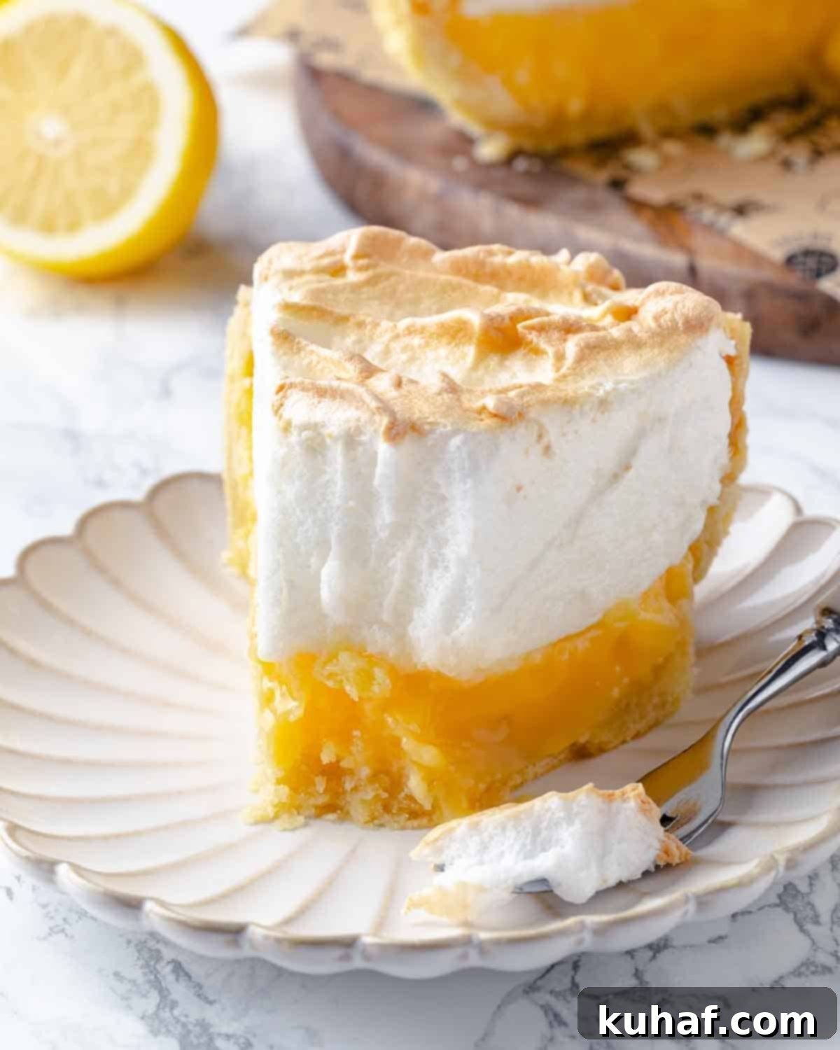A tempting partially eaten slice of lemon meringue pie, with a perfect bite taken out, inviting you to enjoy its delightful layers.