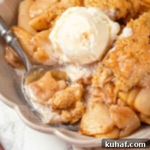 A scoop of vanilla ice cream melting on warm apple cobbler, ready to be enjoyed.