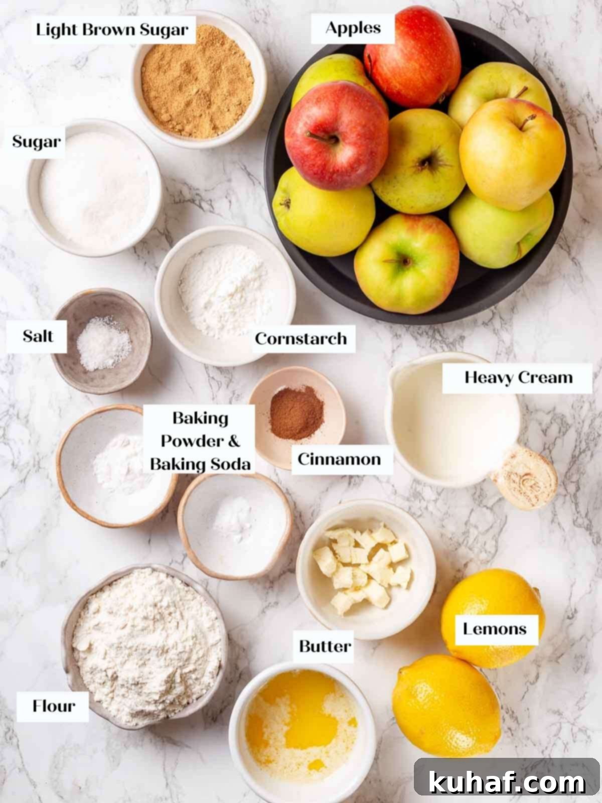 Ingredients for apple cobbler, including apples, sugars, spices, flour, and butter, neatly arranged on a marble surface.