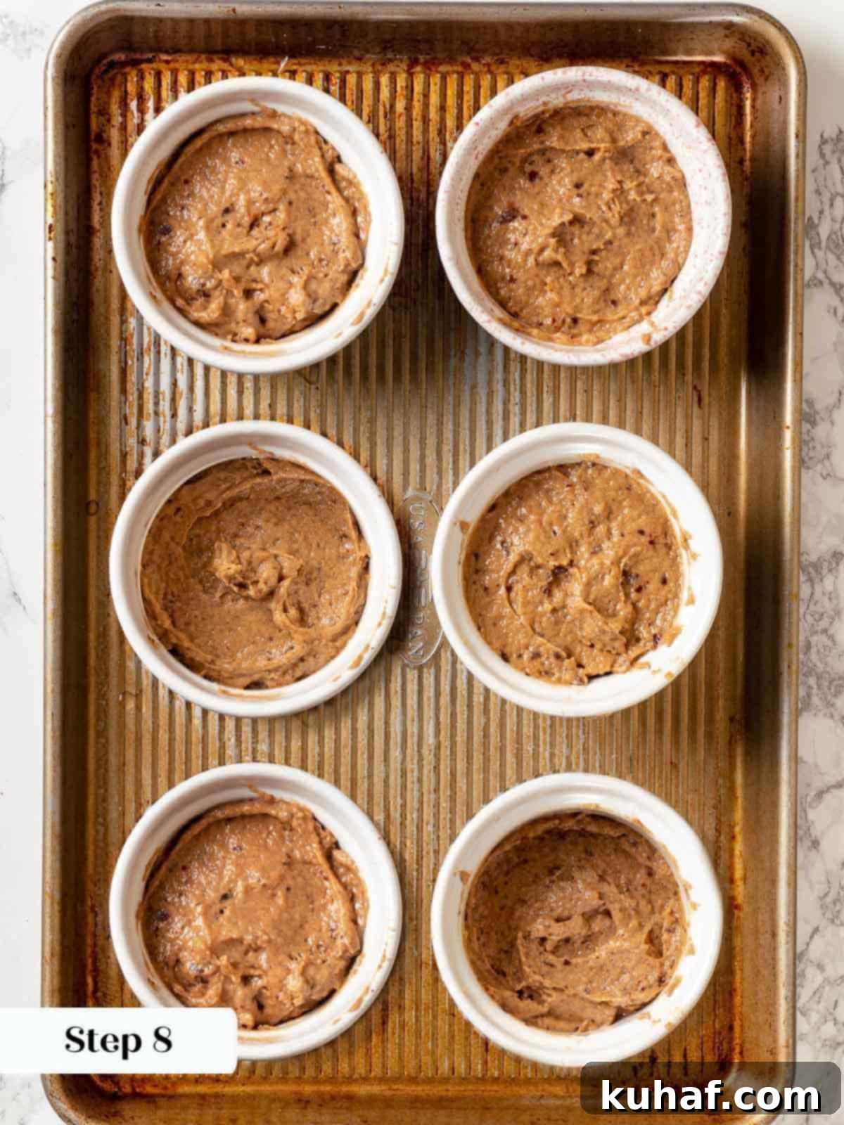 Sticky toffee pudding batter poured into individual ramekins.
