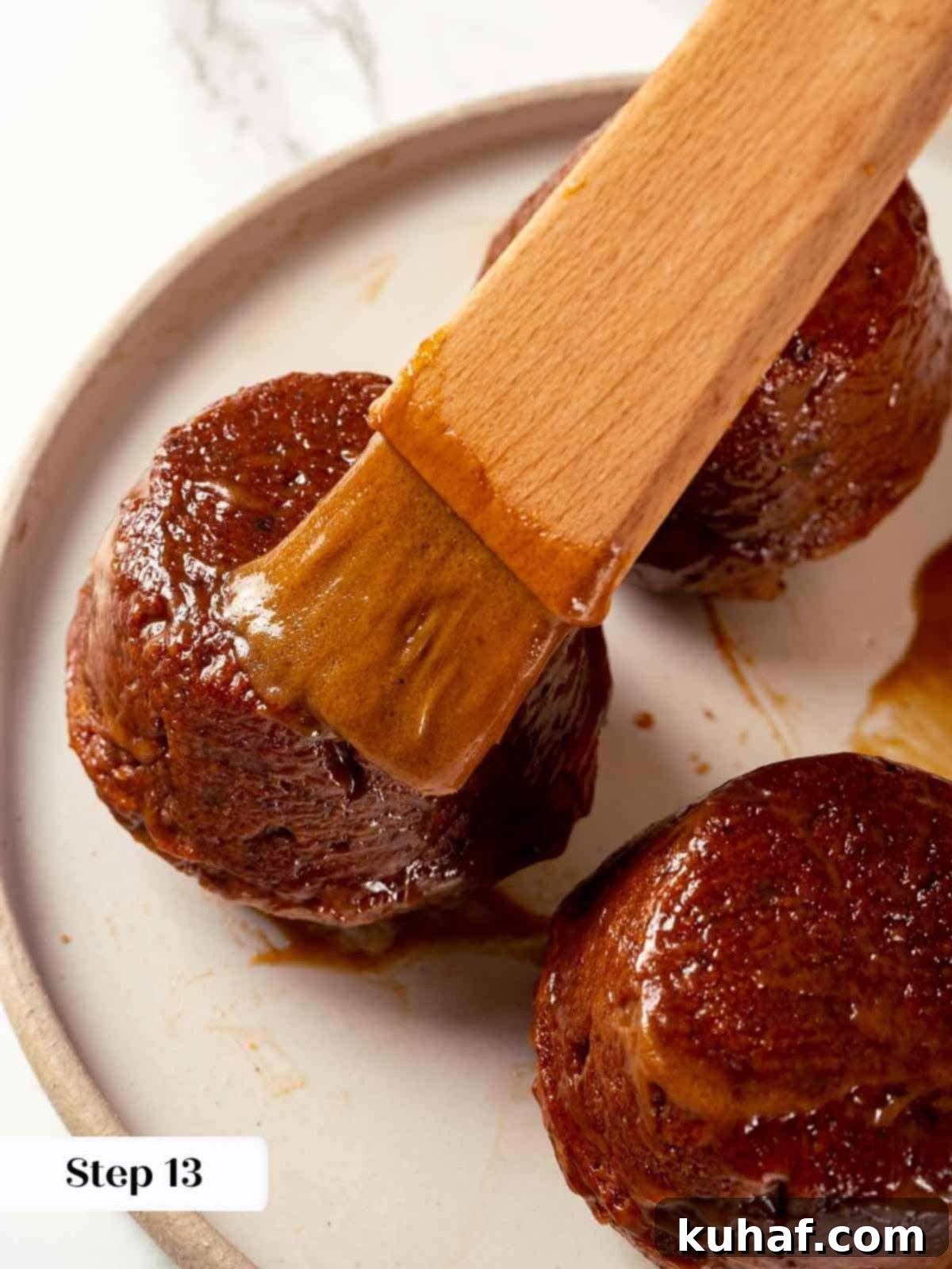 Pastry brush applying glaze on sticky toffee pudding cakes.
