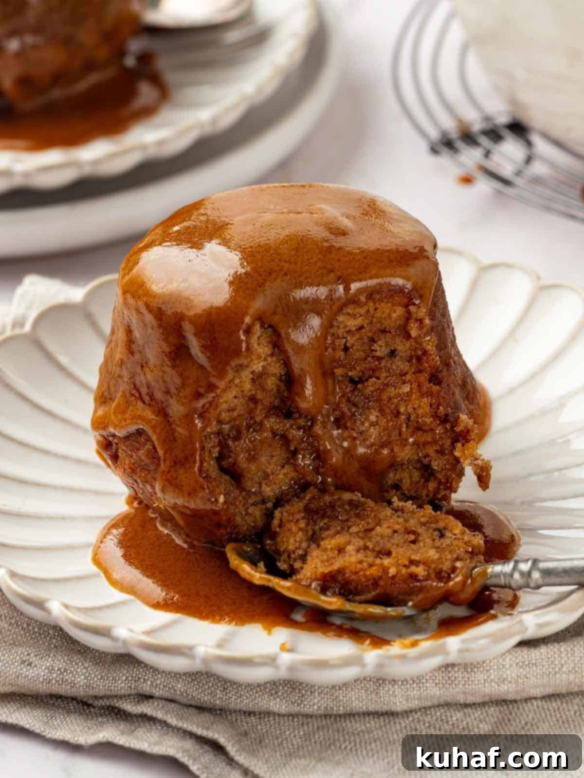 Single serving of sticky toffee pudding on a plate, drizzled with toffee sauce.
