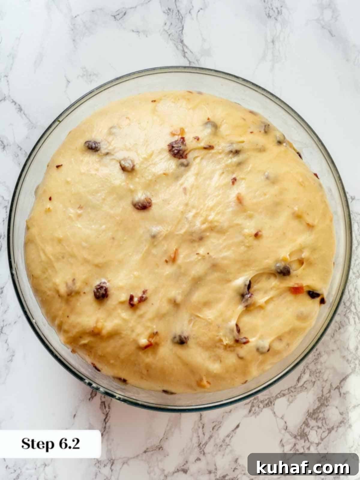 Panettone dough after bulk fermentation, beautifully proofed inside a clear glass bowl, showcasing its airy texture.