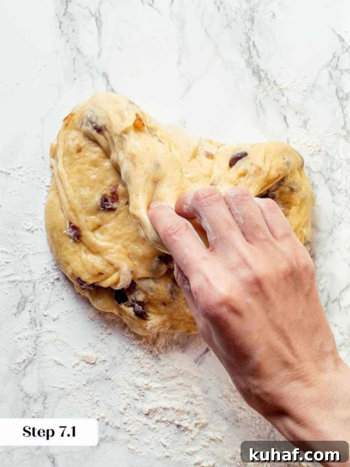 The four corners of the panettone dough carefully folded inward on a clean work surface, preparing for pre-shaping.