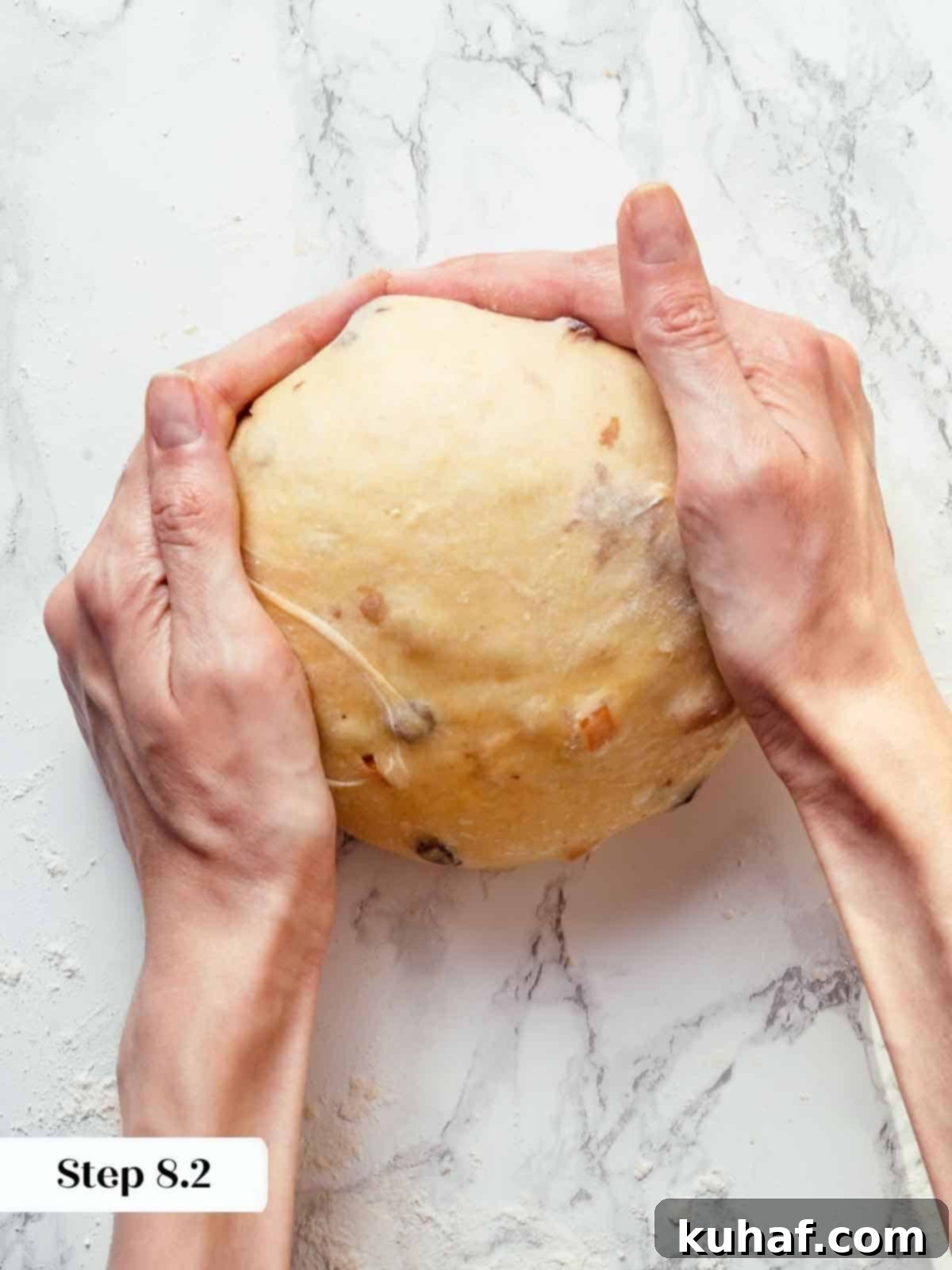 Hands meticulously shaping and tightening panettone dough into a smooth, perfectly round ball for the final presentation.