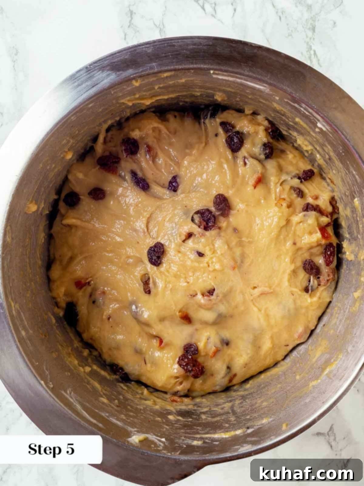The vibrant soaker mixture being added to the panettone dough, ensuring a thorough blend of fruits and citrus.