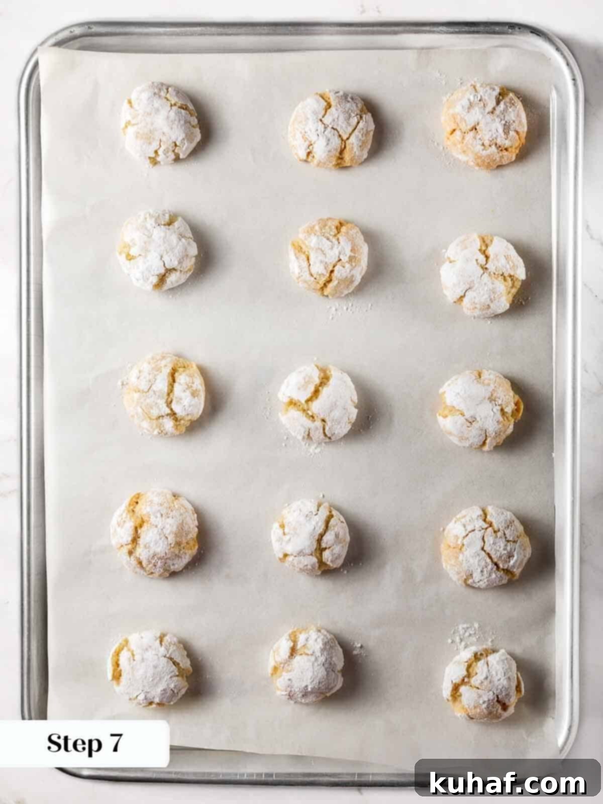 Classic Amaretti Cookies 11 Freshly baked amaretti cookies on a parchment-lined baking sheet, showing their characteristic cracked surface.