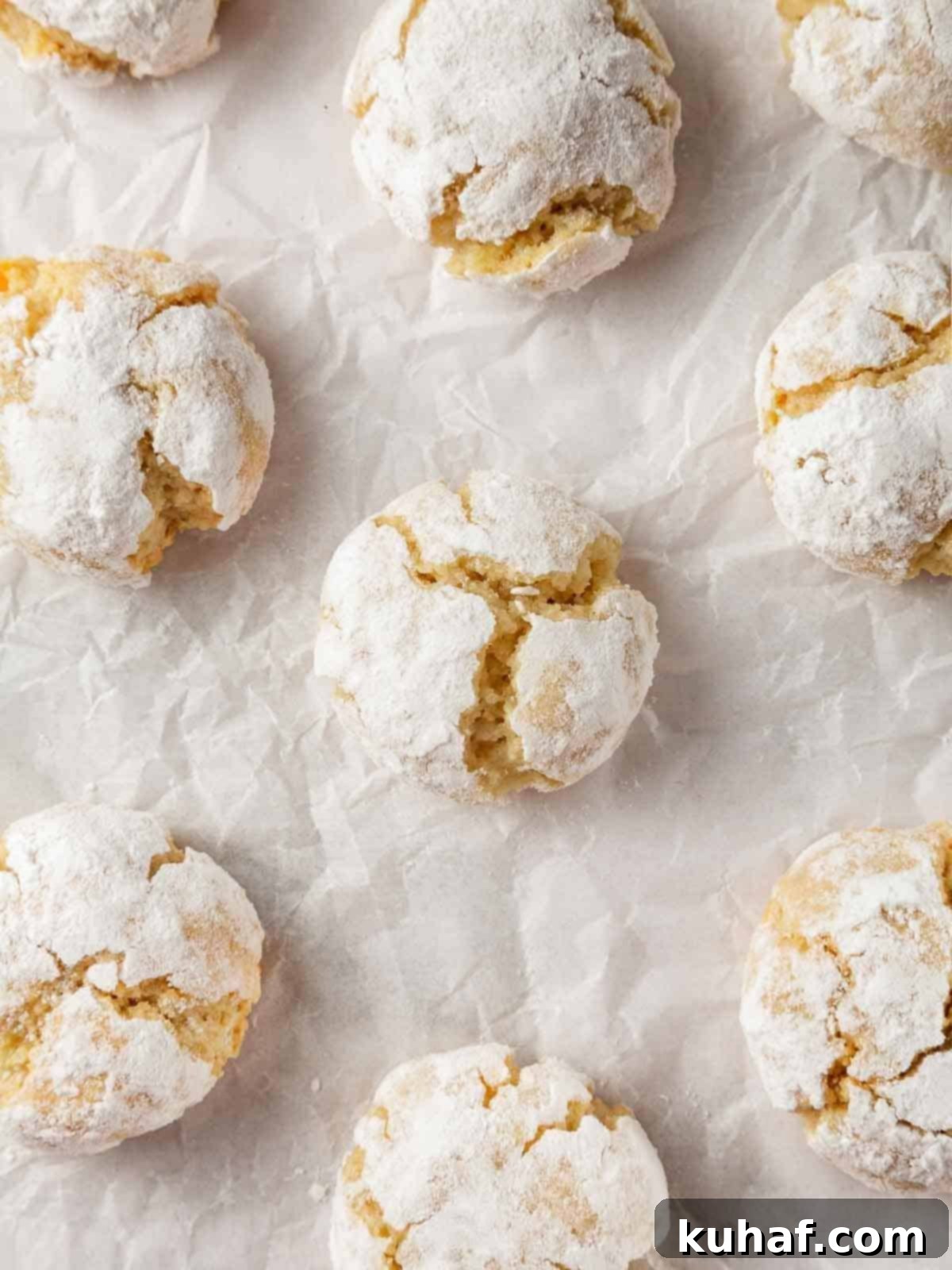 Classic Amaretti Cookies 12 Two freshly baked amaretti cookies, one whole and one broken in half to show its soft, marzipan-like interior.
