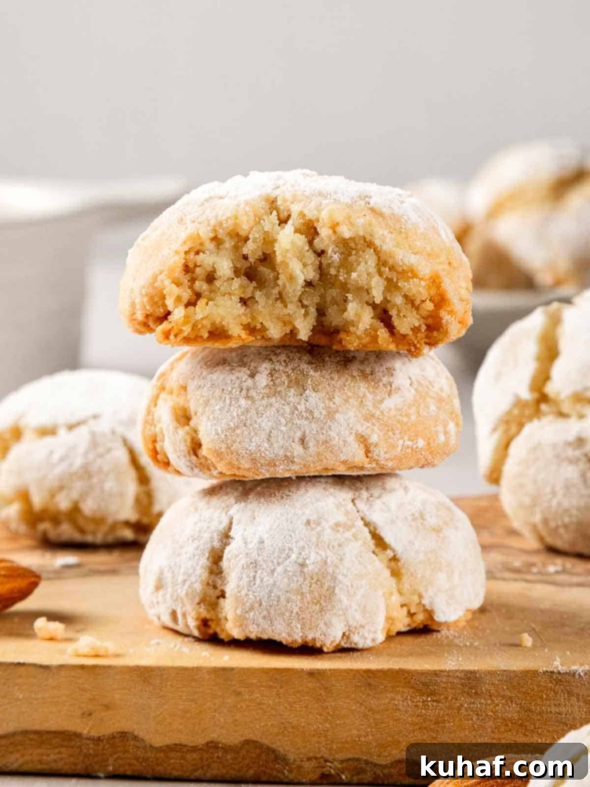 Classic Amaretti Cookies 13 A close-up shot of a single soft amaretti cookie, perfectly crinkled and dusted with powdered sugar, resting on a white surface.