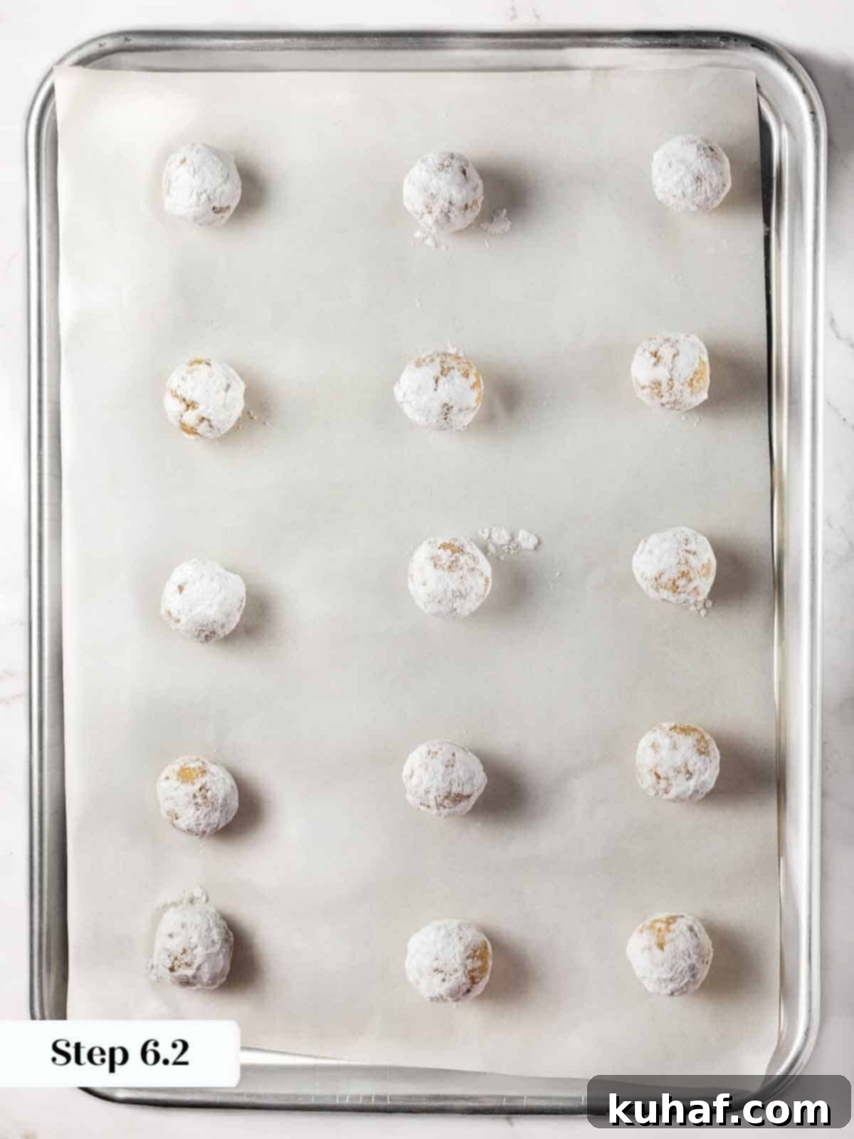 Classic Amaretti Cookies 10 Step-by-step image showing powdered sugar-coated cookie dough balls on a baking sheet.