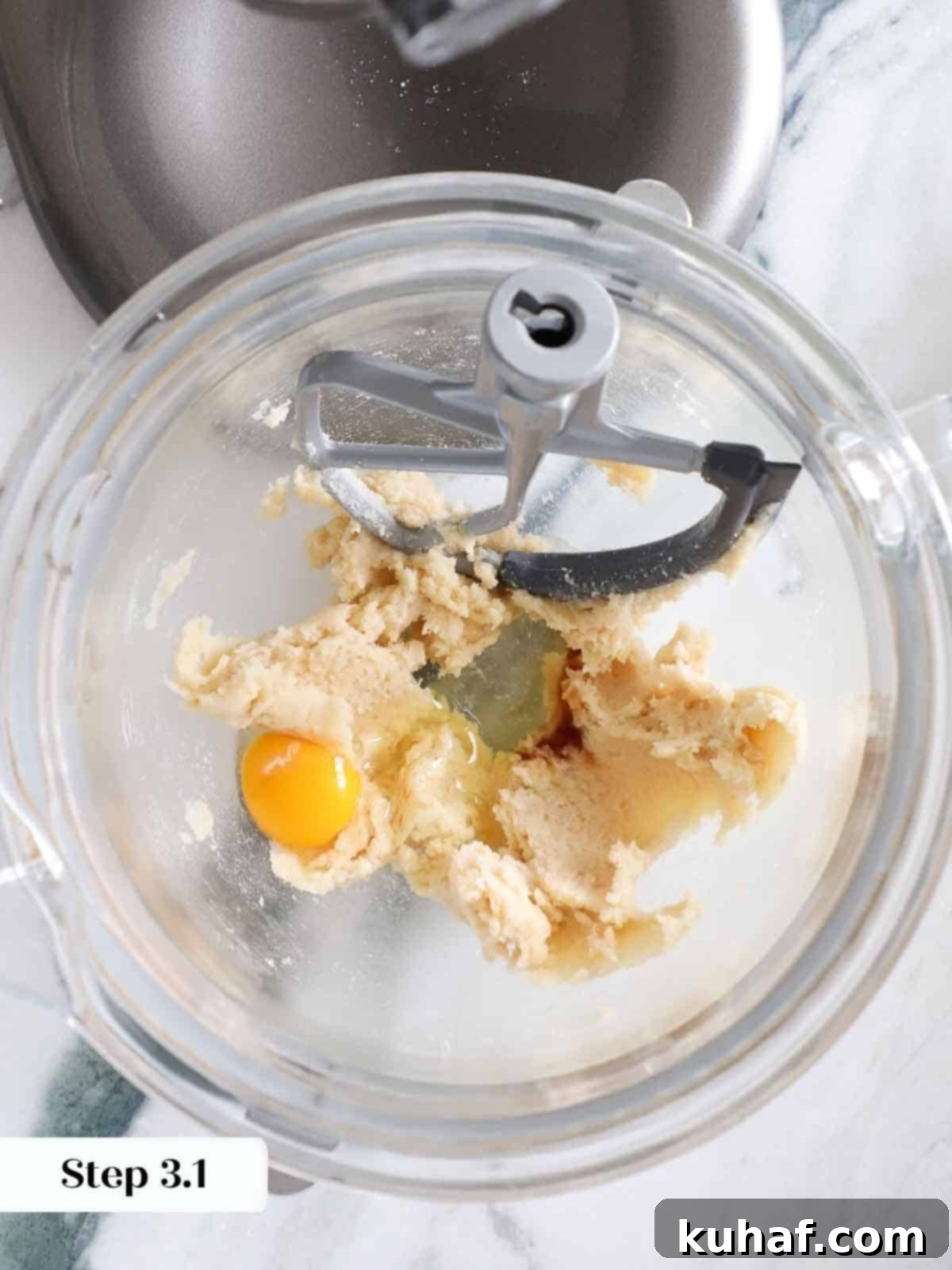 A fresh raw egg being carefully cracked directly into the mixing bowl, poised to be blended into the monster cookie dough mixture.