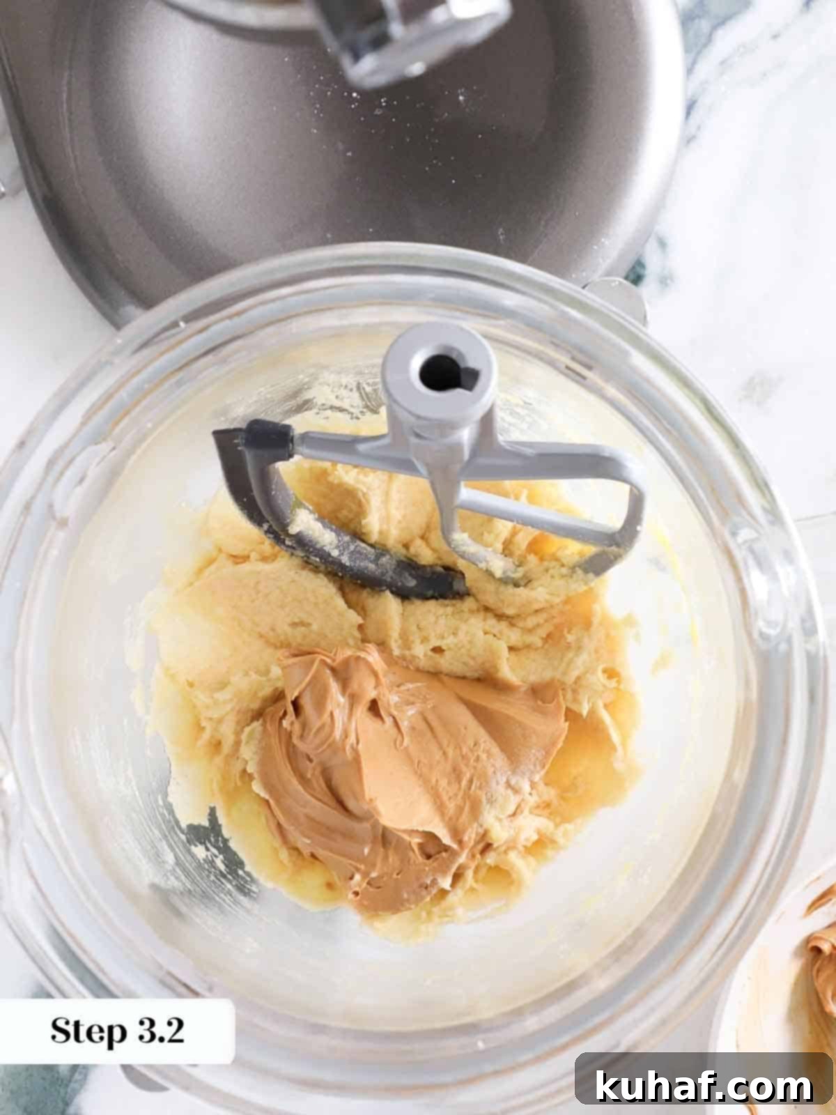 A generous spoonful of creamy, smooth peanut butter being added into the mixing bowl, ready to enrich the monster cookie dough.