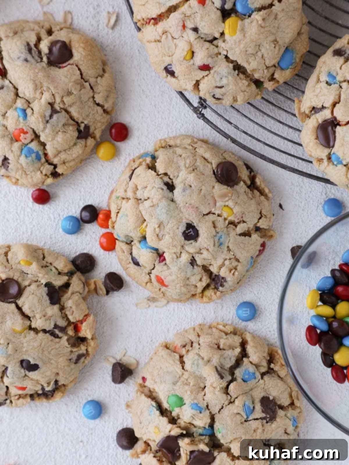 A baking sheet filled with freshly baked monster cookies, showcasing their golden-brown edges and colorful M&M's on the surface.