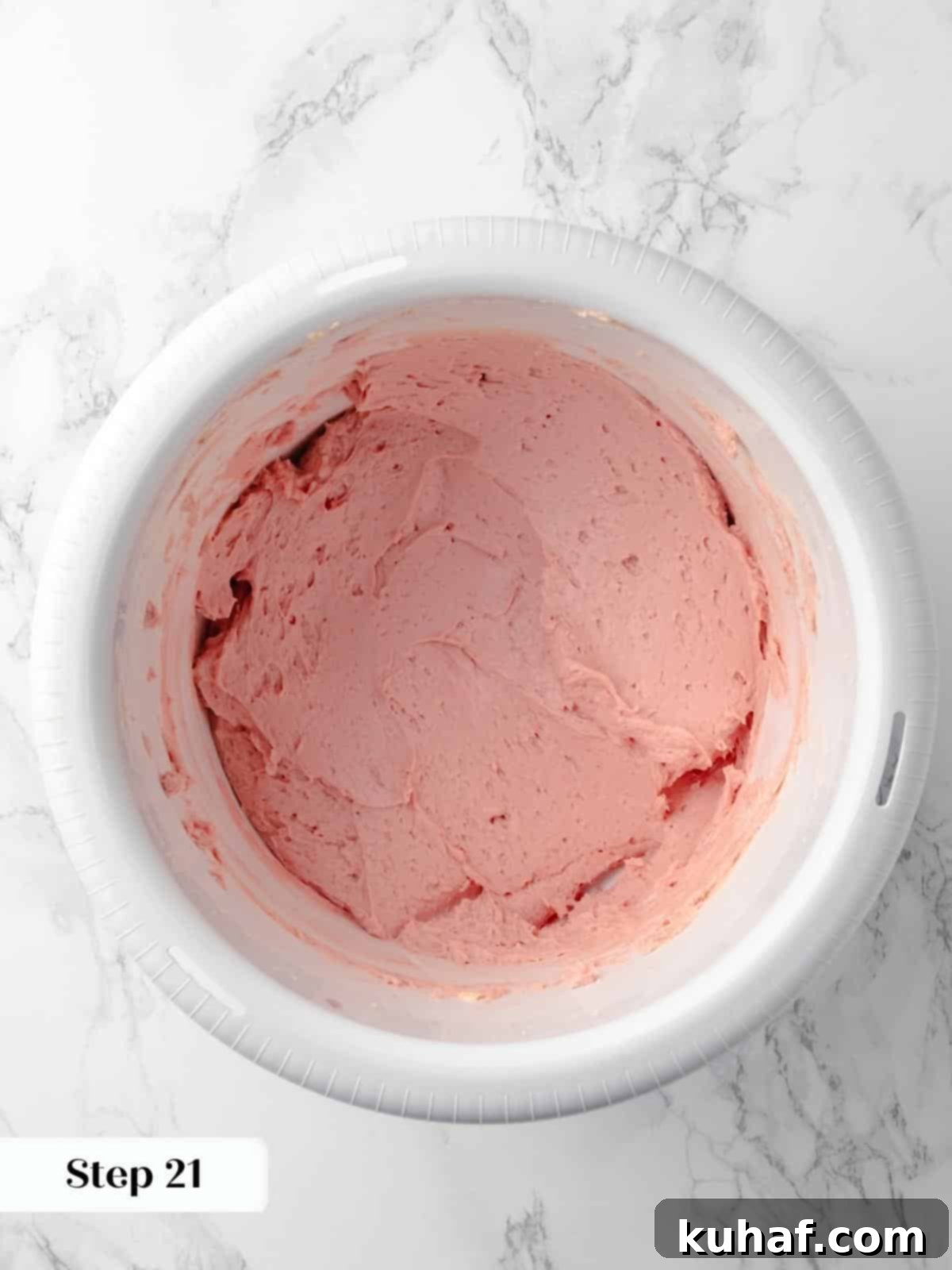 A bowl of beautifully swirled pink raspberry buttercream frosting, smooth and ready to be used for filling and decorating the cake.